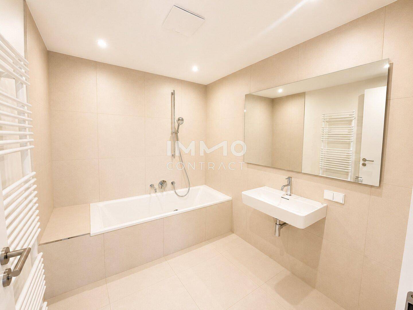 Modernes Badezimmer mit Badewanne, schwebendem Waschbecken und großem Spiegel.