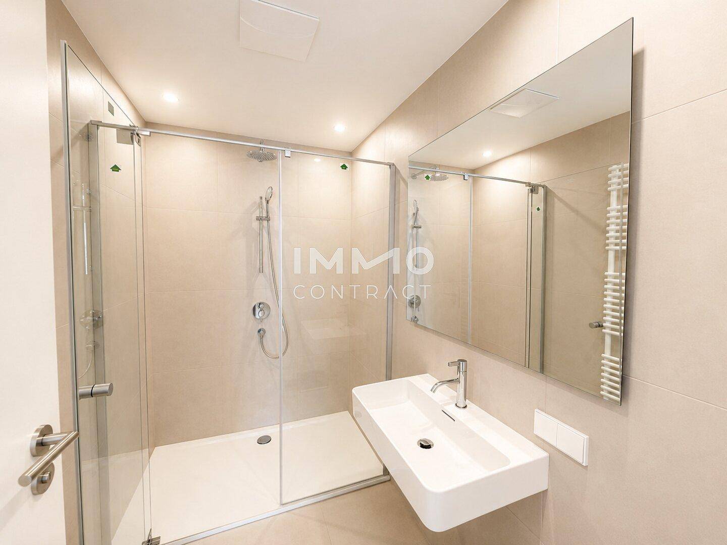 Modernes Badezimmer mit begehbarer Dusche, großem Spiegel und beheiztem Handtuchhalter.