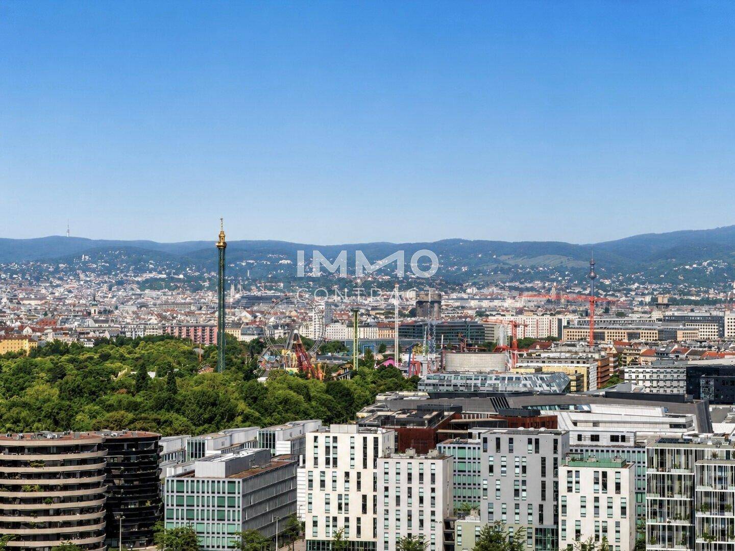 Panoramablick über die Stadt mit vielen Gebäuden und grünen Hügeln im Hintergrund.