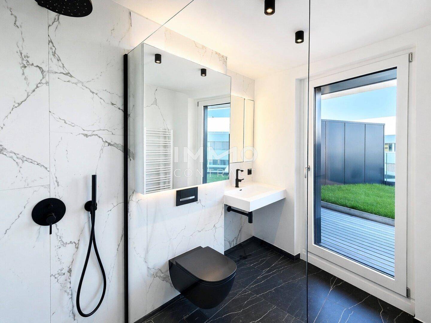 Modernes Badezimmer mit Marmorfliesen, schwarzer Toilette und bodengleicher Dusche mit Fenster.