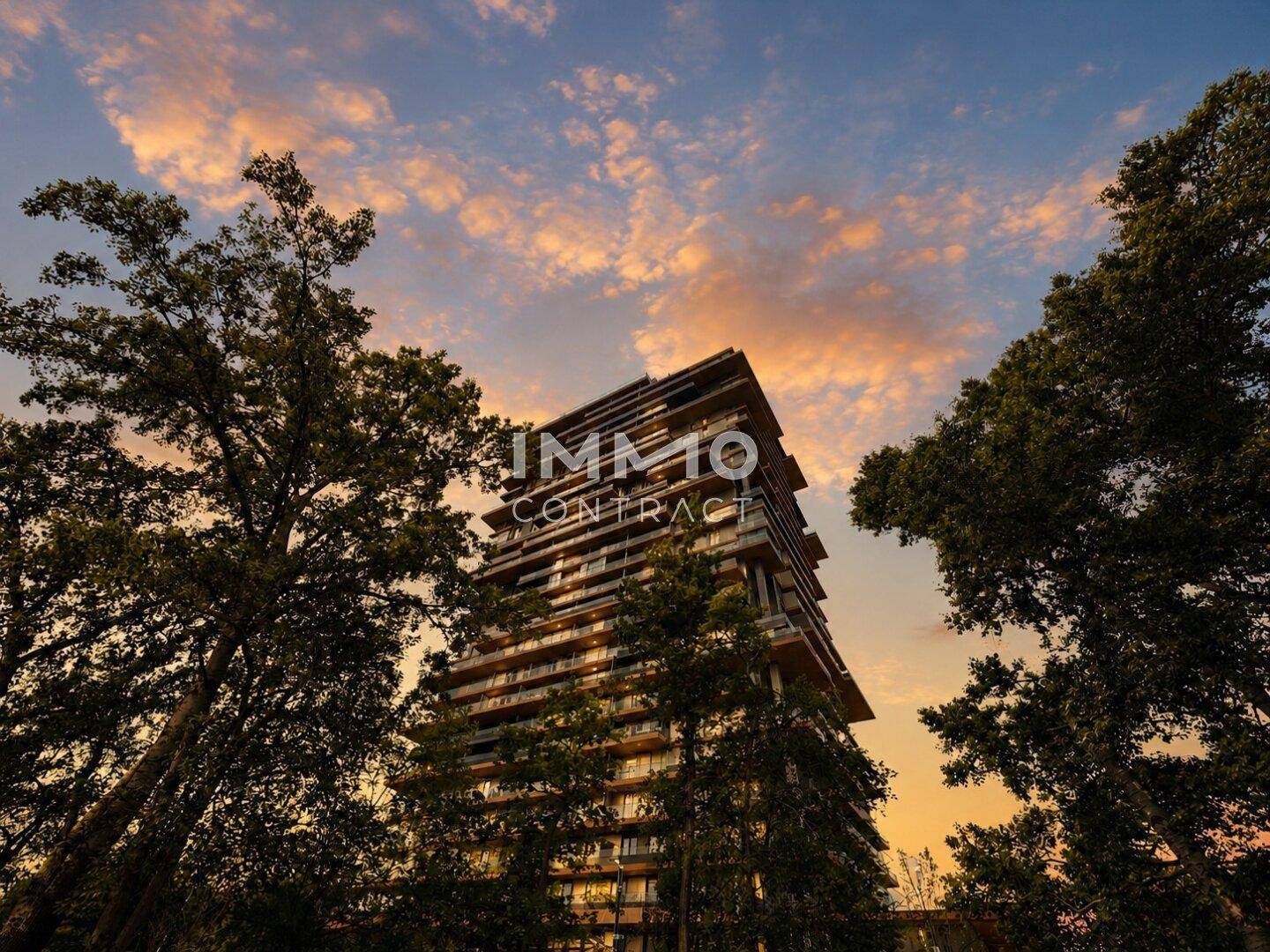 Beeindruckendes Hochhaus bei Sonnenuntergang, umgeben von Bäumen und warmem Licht.