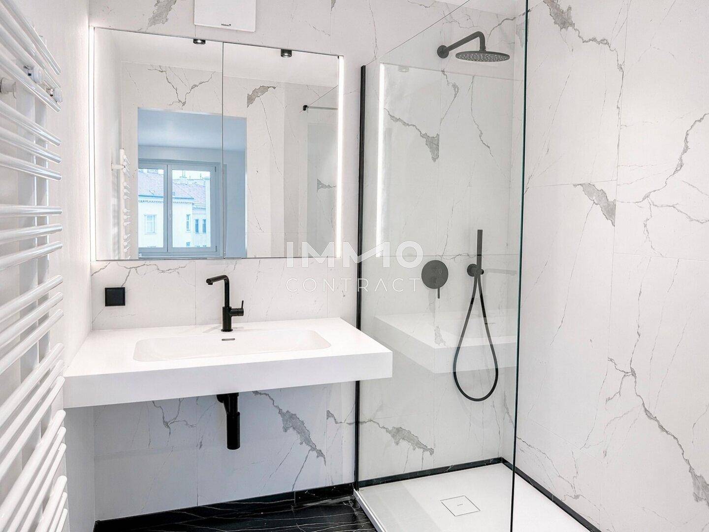 Modernes Badezimmer mit Marmorfliesen, begehbarer Dusche und schwarzer Armatur.