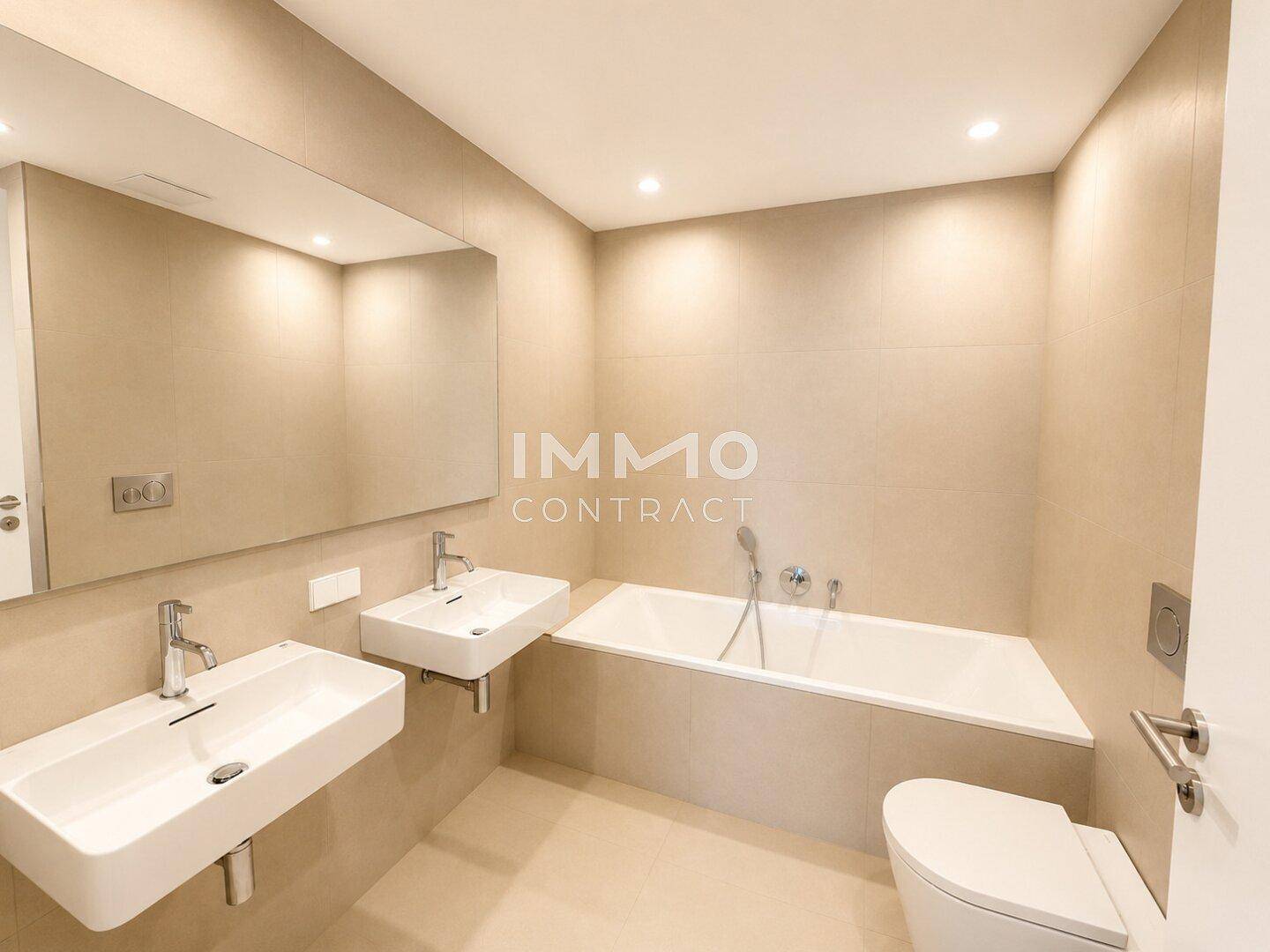 Modernes Badezimmer mit zwei Waschbecken, Badewanne und großen beigefarbenen Fliesen.