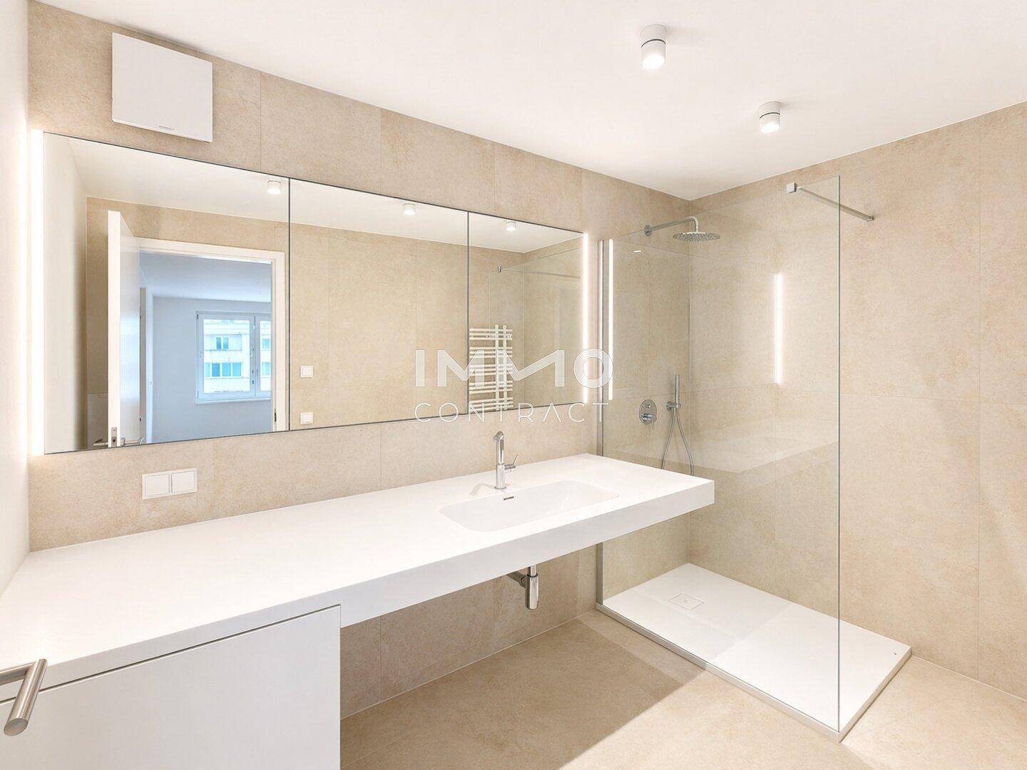 Modernes Badezimmer mit großer Spiegelfront, Einzelwaschbecken und ebenerdiger Dusche.