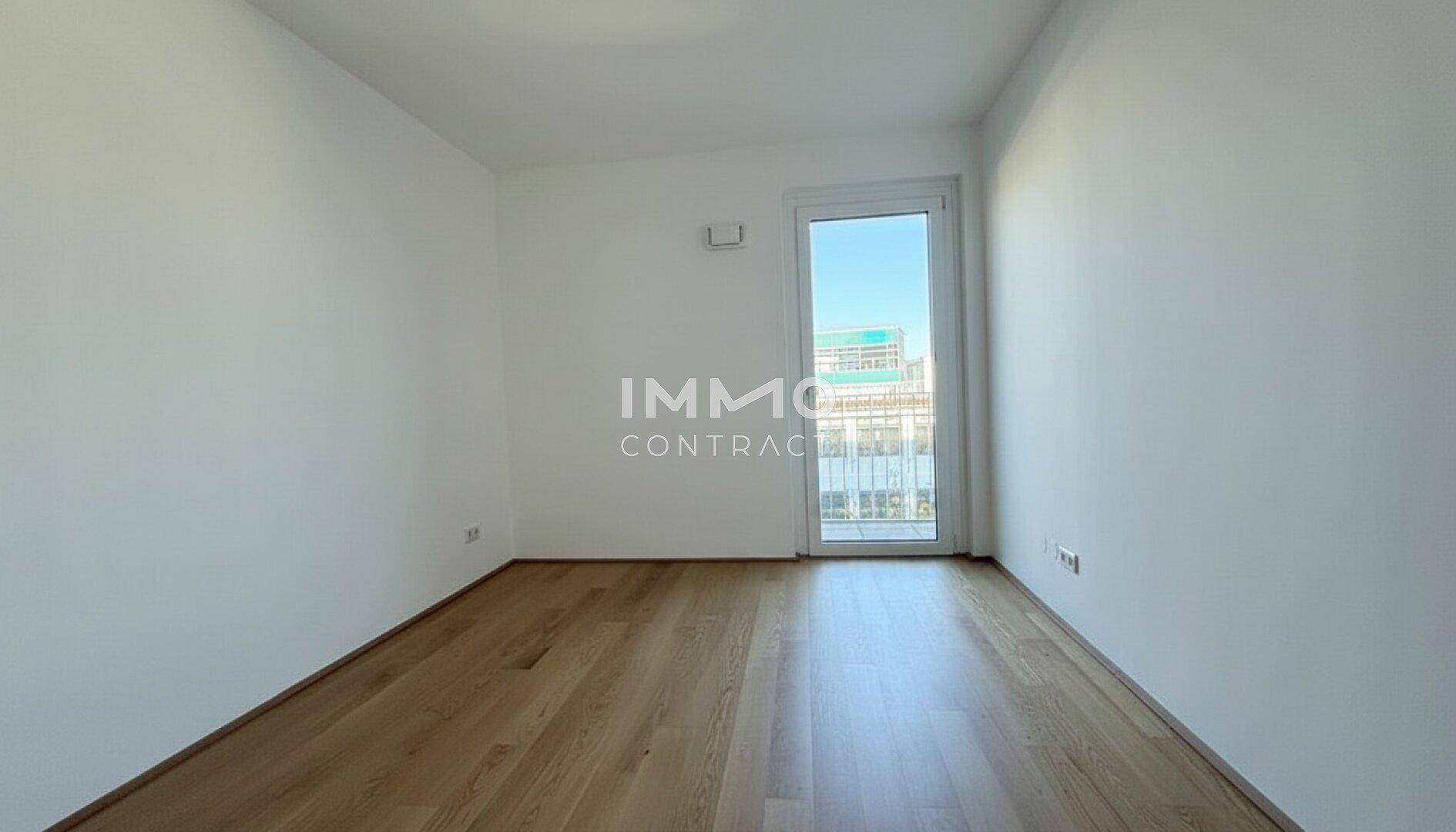 Leeres Zimmer mit Holzboden und Fenstertür, ideal als Schlaf- oder Arbeitszimmer nutzbar.