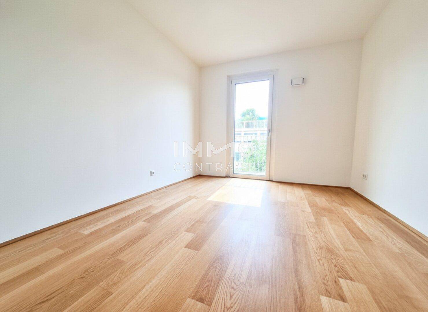 Ruhiges Schlafzimmer mit hellem Parkettboden und Fenster für viel Tageslicht.