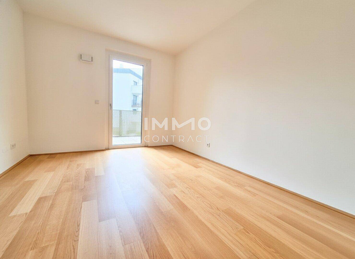 Helles Schlafzimmer mit Holzboden und Zugang zu einem kleinen Balkon oder einer französischen Balkontür.
