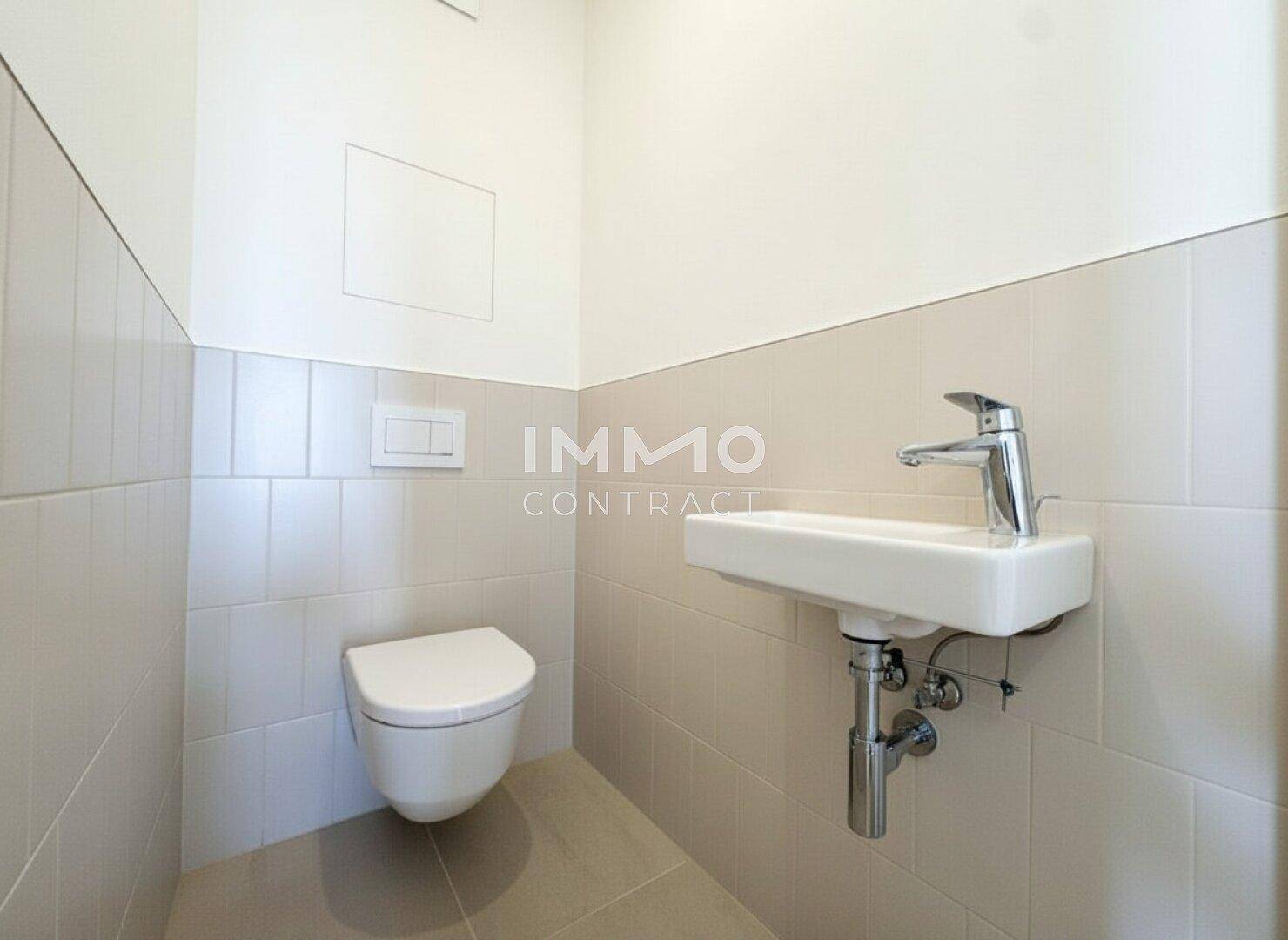 Funktionales Gäste-WC mit wandhängender Toilette und kleinem Handwaschbecken.