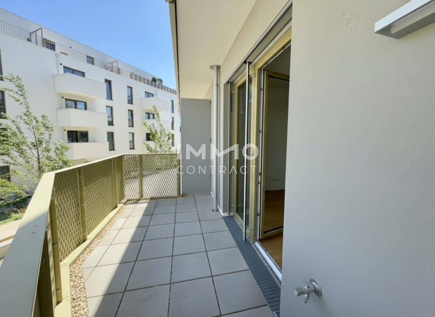 Geräumiger Balkon mit Fliesenboden und Blick auf die moderne Wohnanlage.