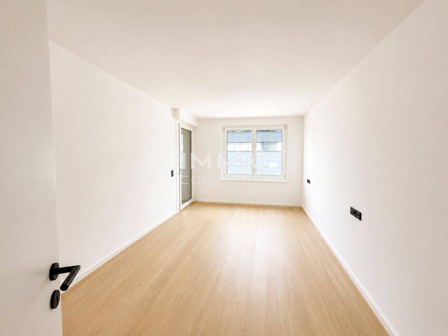 Helles Schlafzimmer mit Parkettboden und großem Fenster, bereit zur individuellen Gestaltung.