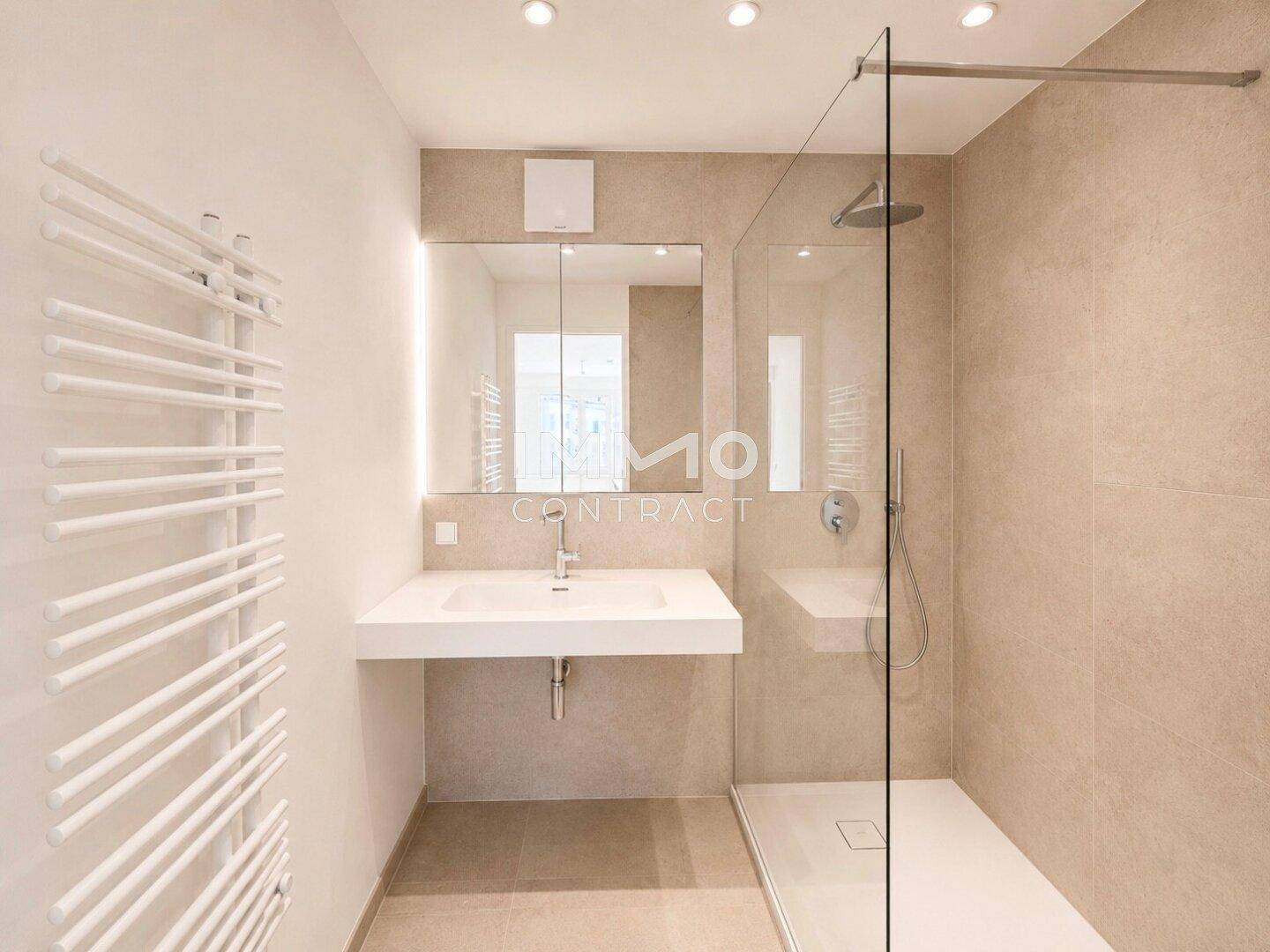 Modernes Badezimmer mit begehbarer Dusche, beigen Fliesen und einem eleganten Waschtisch.