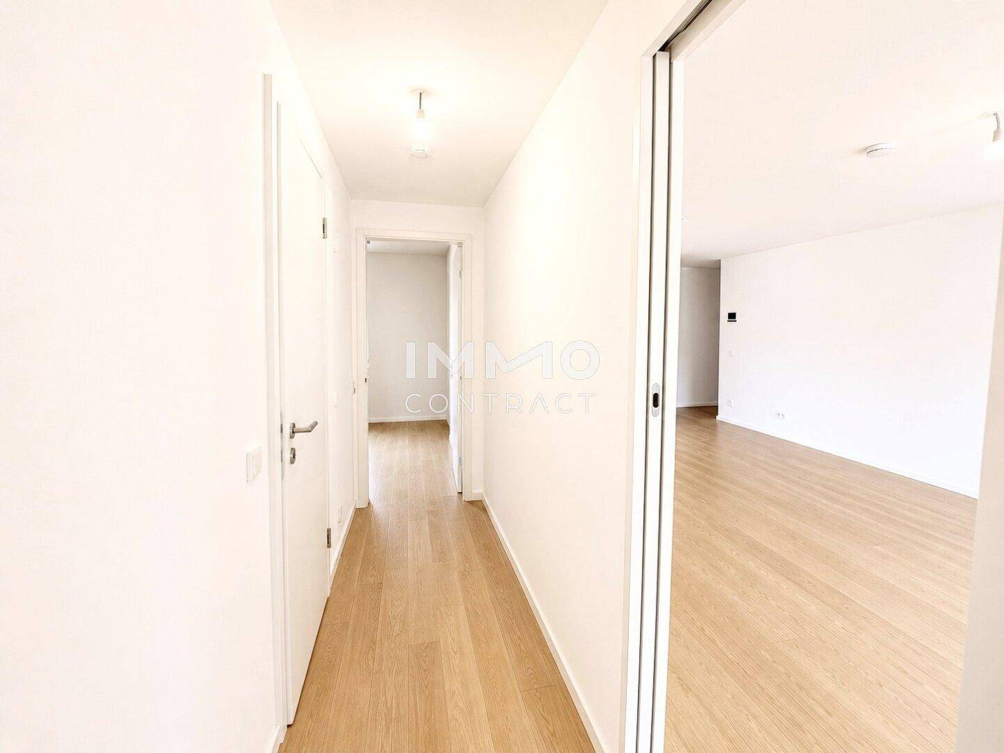 Heller Flur mit Holzboden, der zu verschiedenen Räumen der Wohnung führt.