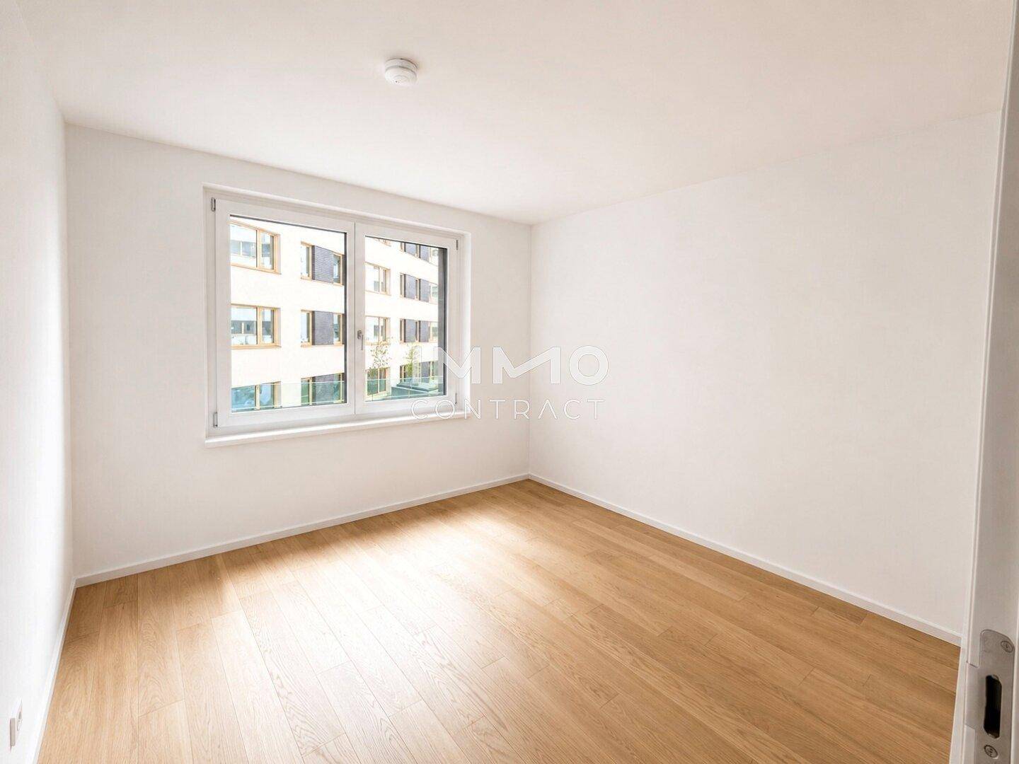 Helles Schlafzimmer mit Parkettboden und großem Fenster, bereit zur Einrichtung.