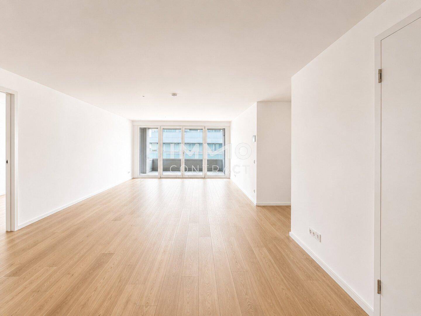 Geräumiges, helles Wohnzimmer mit Parkettboden und Zugang zu einem Balkon.