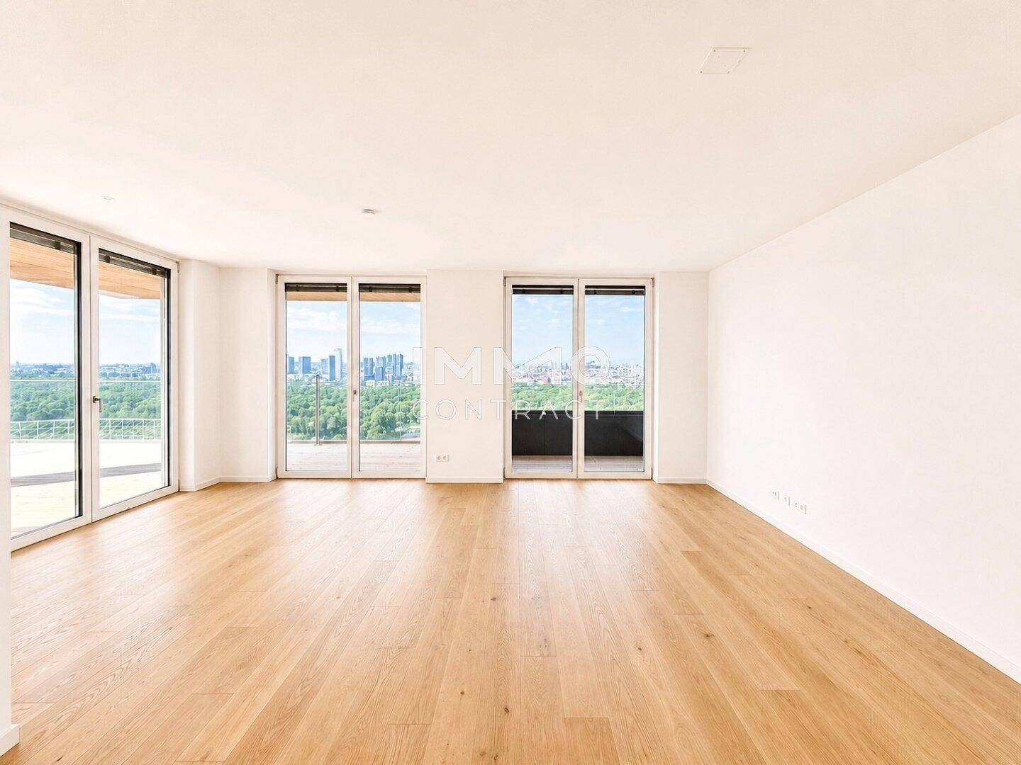 Heller, geräumiger Wohnbereich mit Parkettboden und großen Fenstern, die einen weiten Blick auf die Stadt bieten.