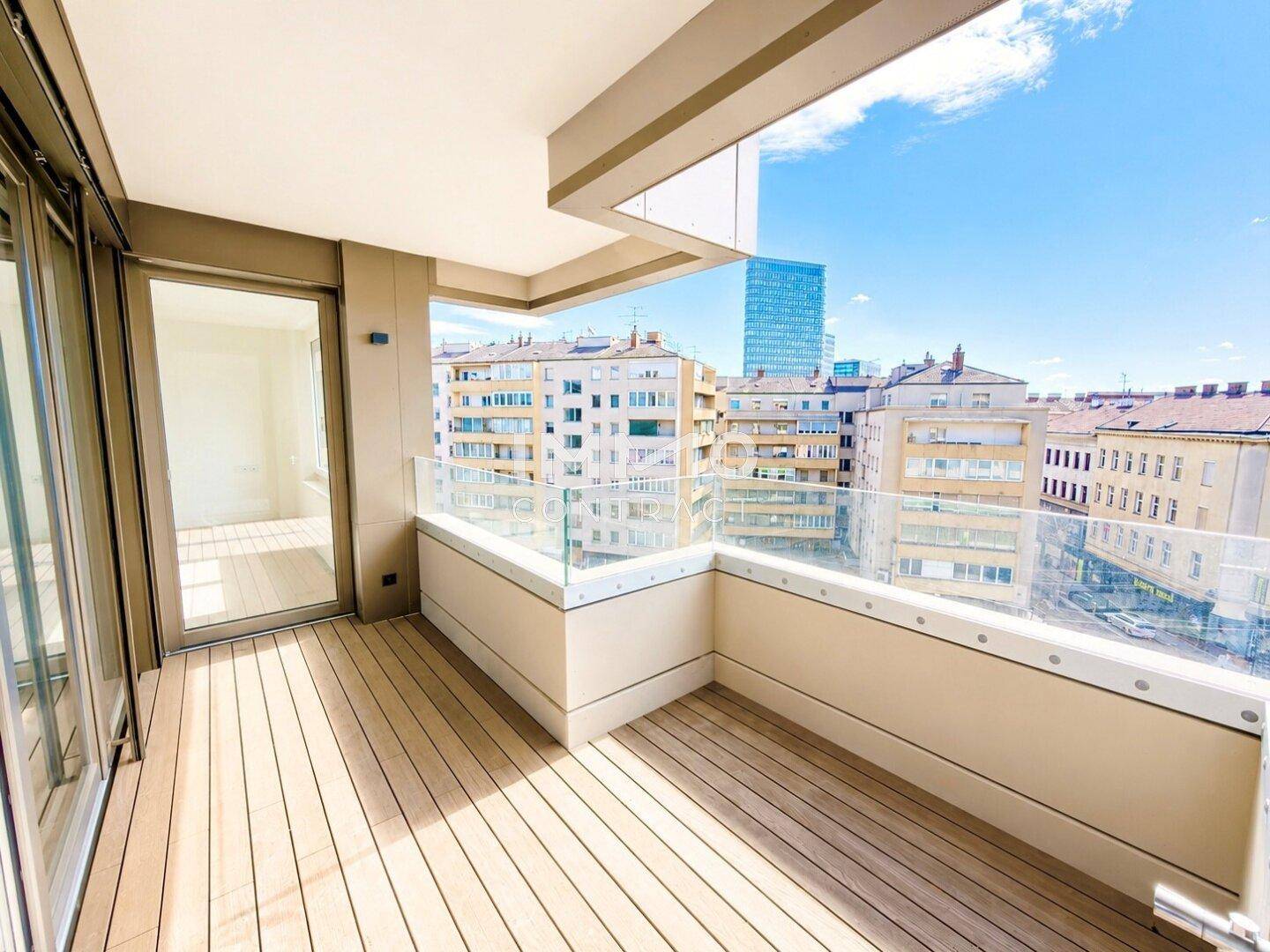 Moderner Balkon mit Holzboden und Glasgeländer, bietet einen weiten Stadtblick.