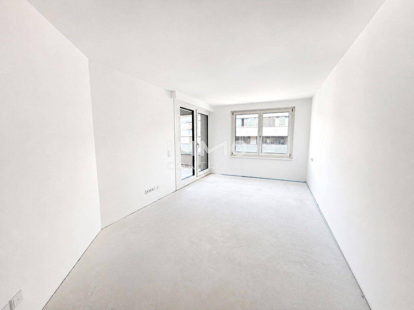 Leeres Zimmer mit Fenster und Zugang zu einem Balkon oder einer Terrasse.