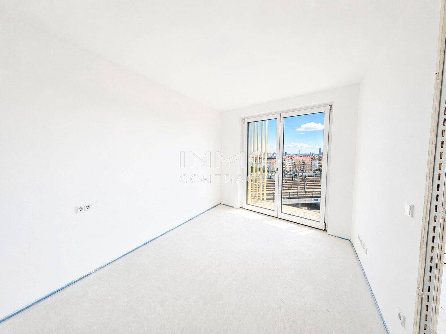 Helles Zimmer mit großem Fenster und Teppichboden, bietet einen schönen Ausblick auf die Stadt.