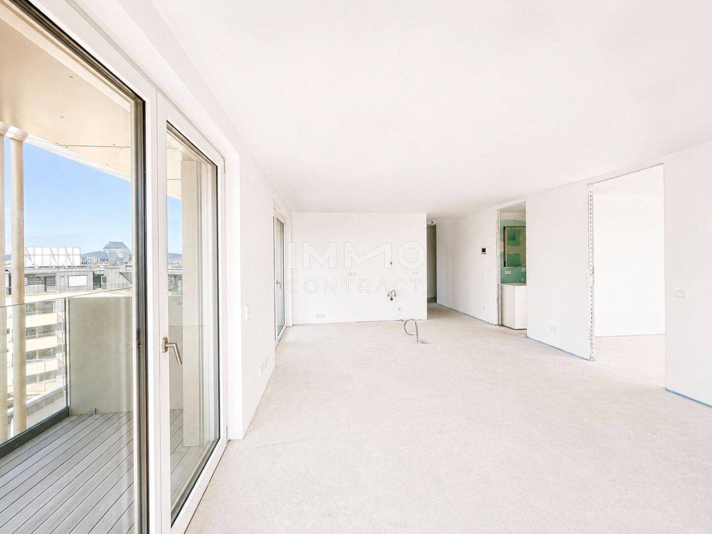 Heller, offener Wohnbereich mit großen Fenstern und Zugang zu einem Balkon.