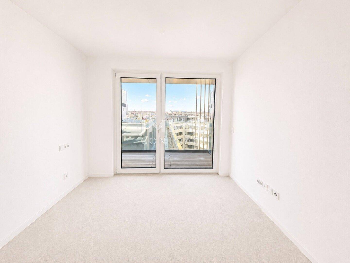 Helles Schlafzimmer mit großen Fenstern und Zugang zu einem Balkon, bietet Stadtblick.
