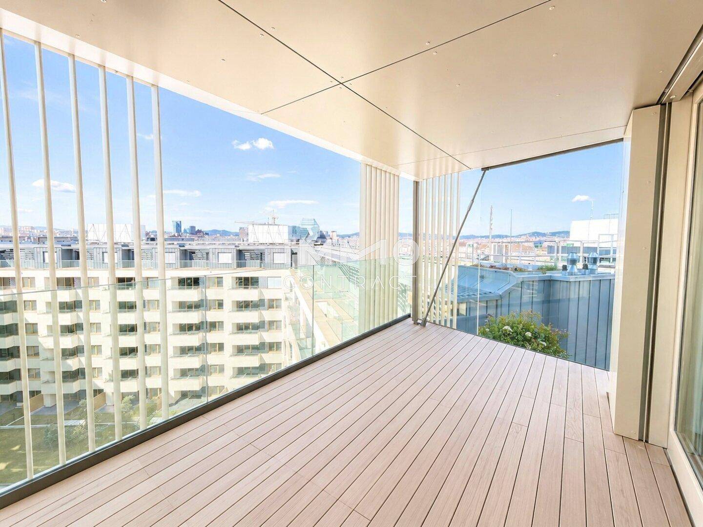 Geräumiger Balkon mit Holzboden und weitem Blick über die Stadt.