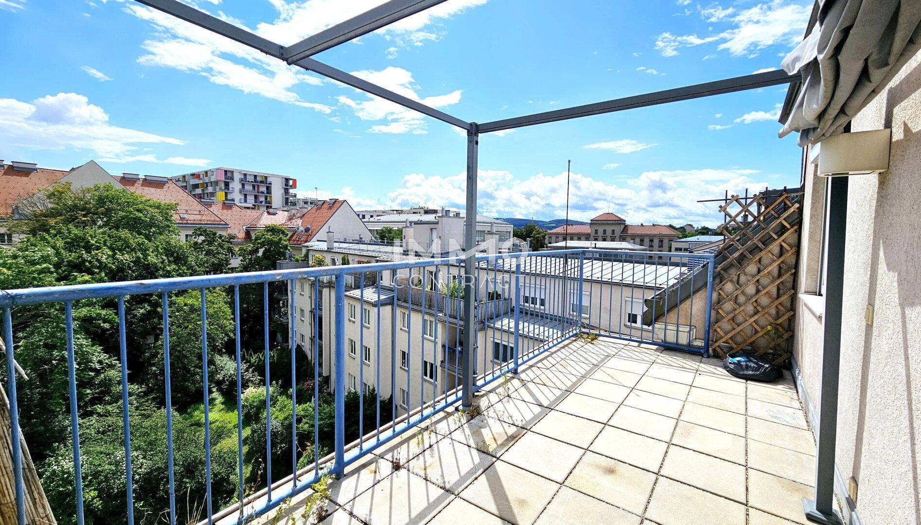 Geräumige Dachterrasse mit Metallgeländer und weitem Blick über die umliegende Bebauung.