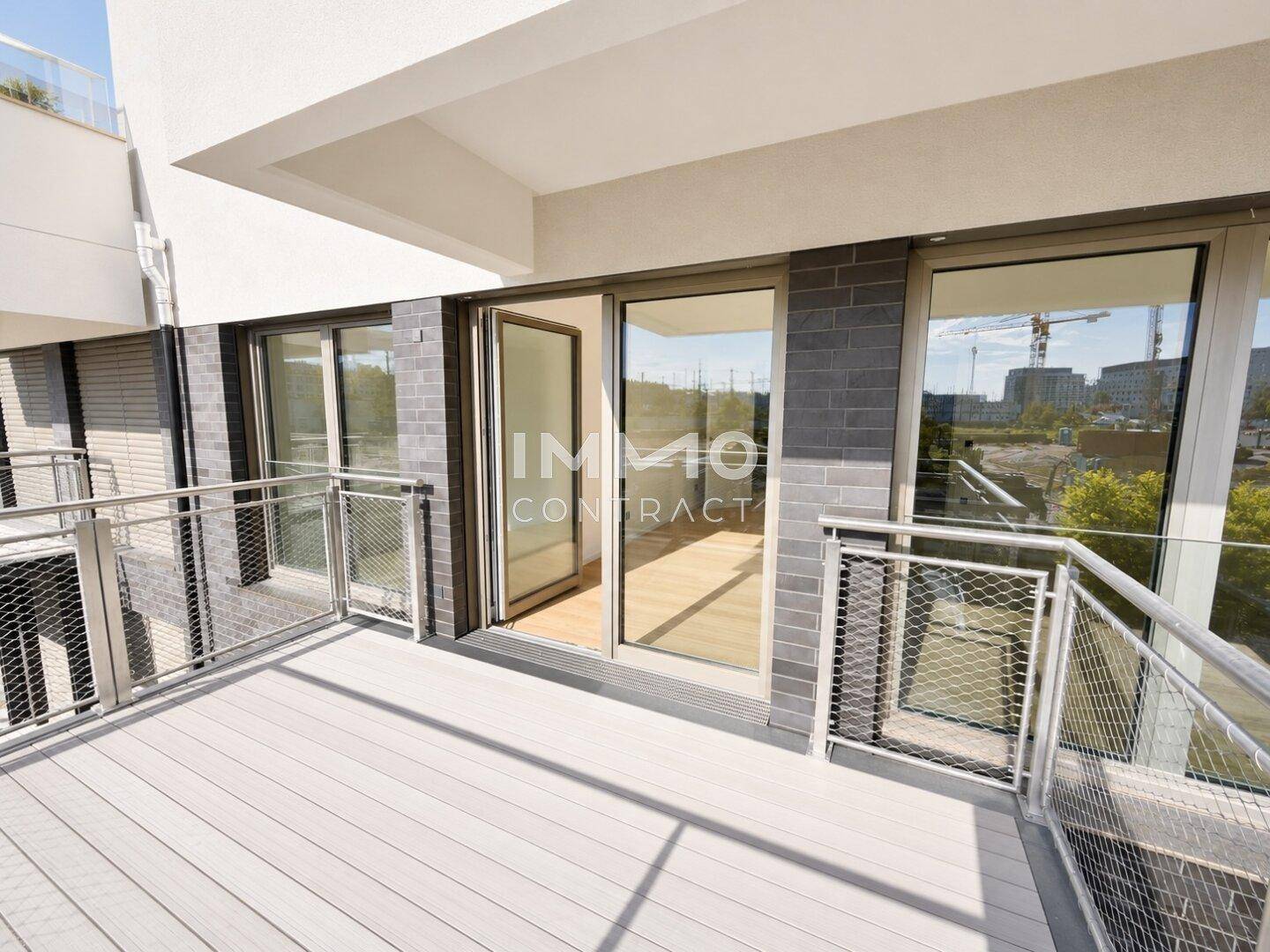 Geräumiger Balkon mit modernem Bodenbelag und Metallgeländer, mit Blick auf die Umgebung.