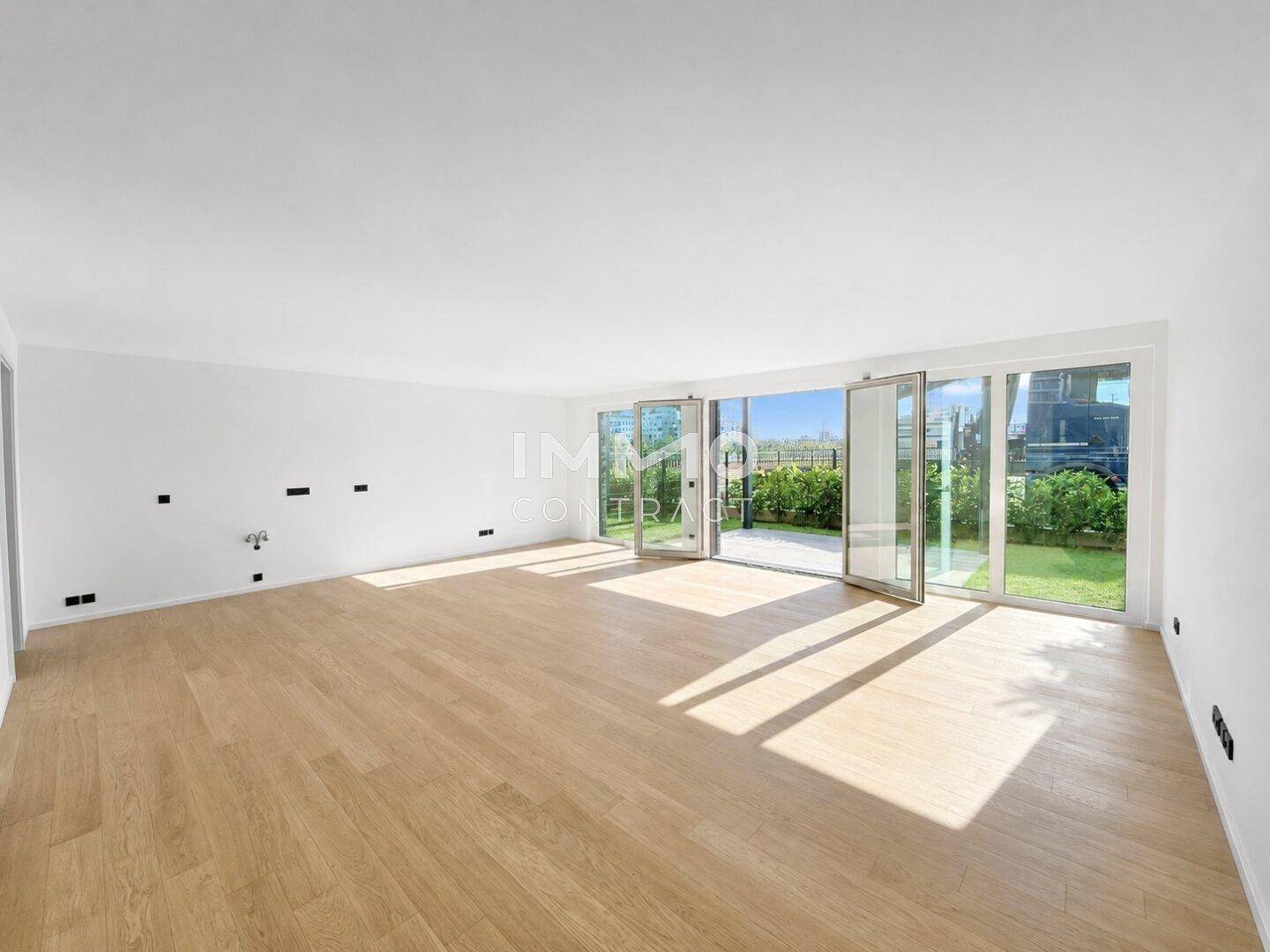 Geräumiges, helles Wohnzimmer mit Holzboden und großen Glasfronten zum Garten.