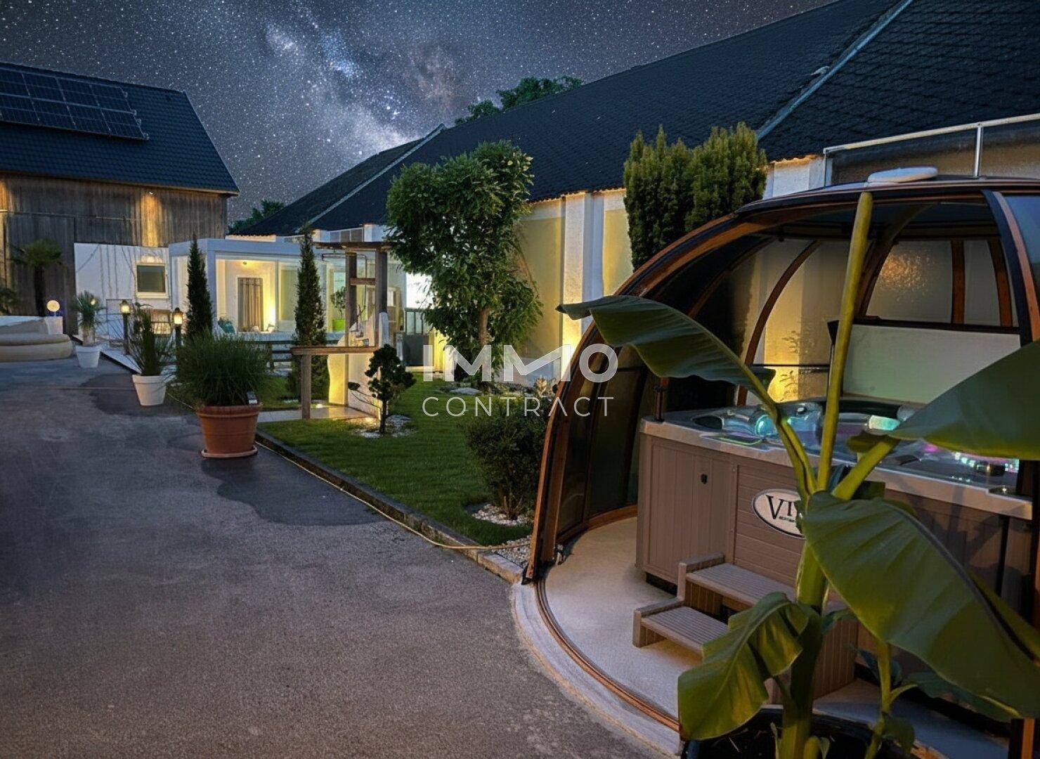 Entspannender Außenbereich bei Nacht mit Whirlpool in einer Kuppel und gepflegtem Garten.