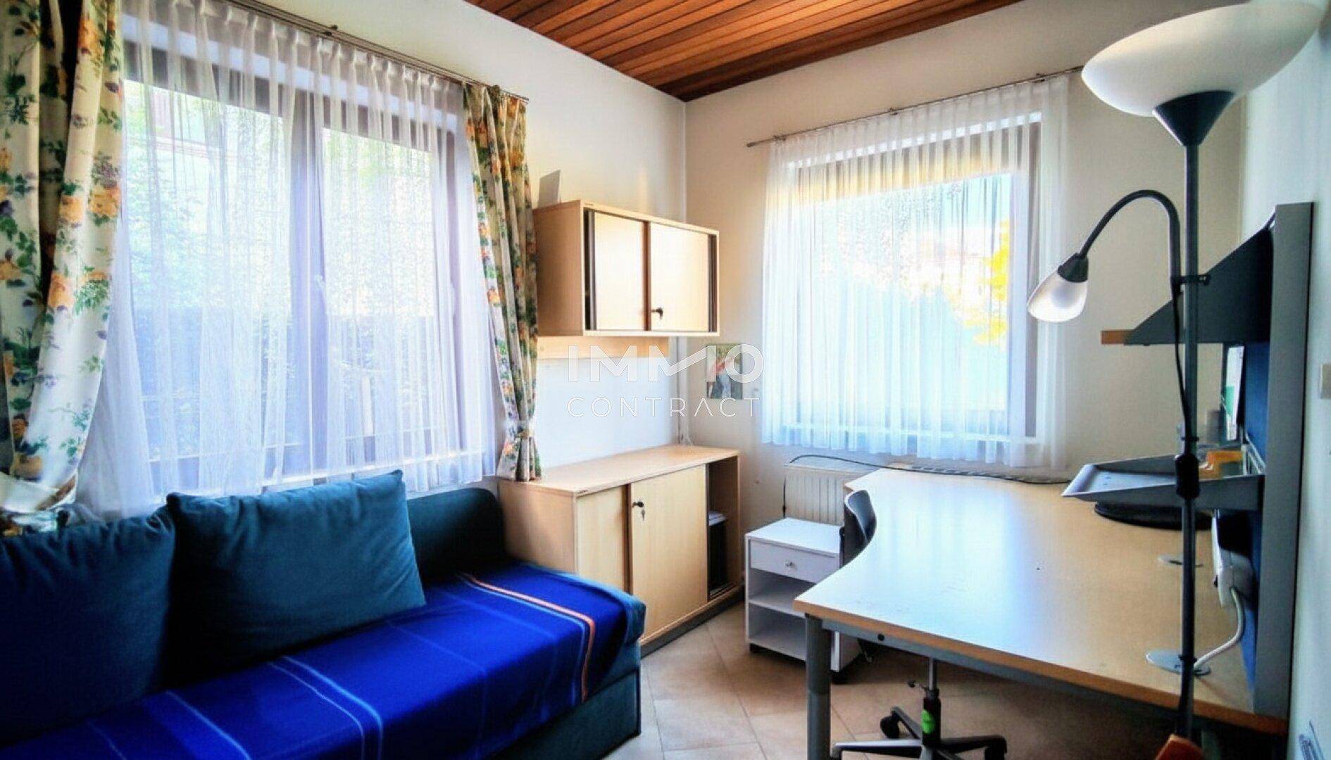 Helles Arbeitszimmer mit Schreibtisch, Sofa und Holzbalkendecke, ideal für Home-Office.
