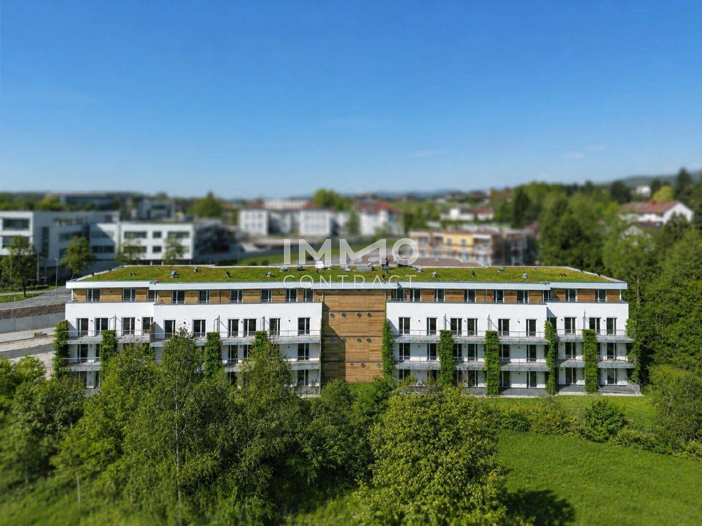 Luftaufnahme einer weitläufigen Wohnanlage mit begrünten Dächern, eingebettet in grüne Umgebung.