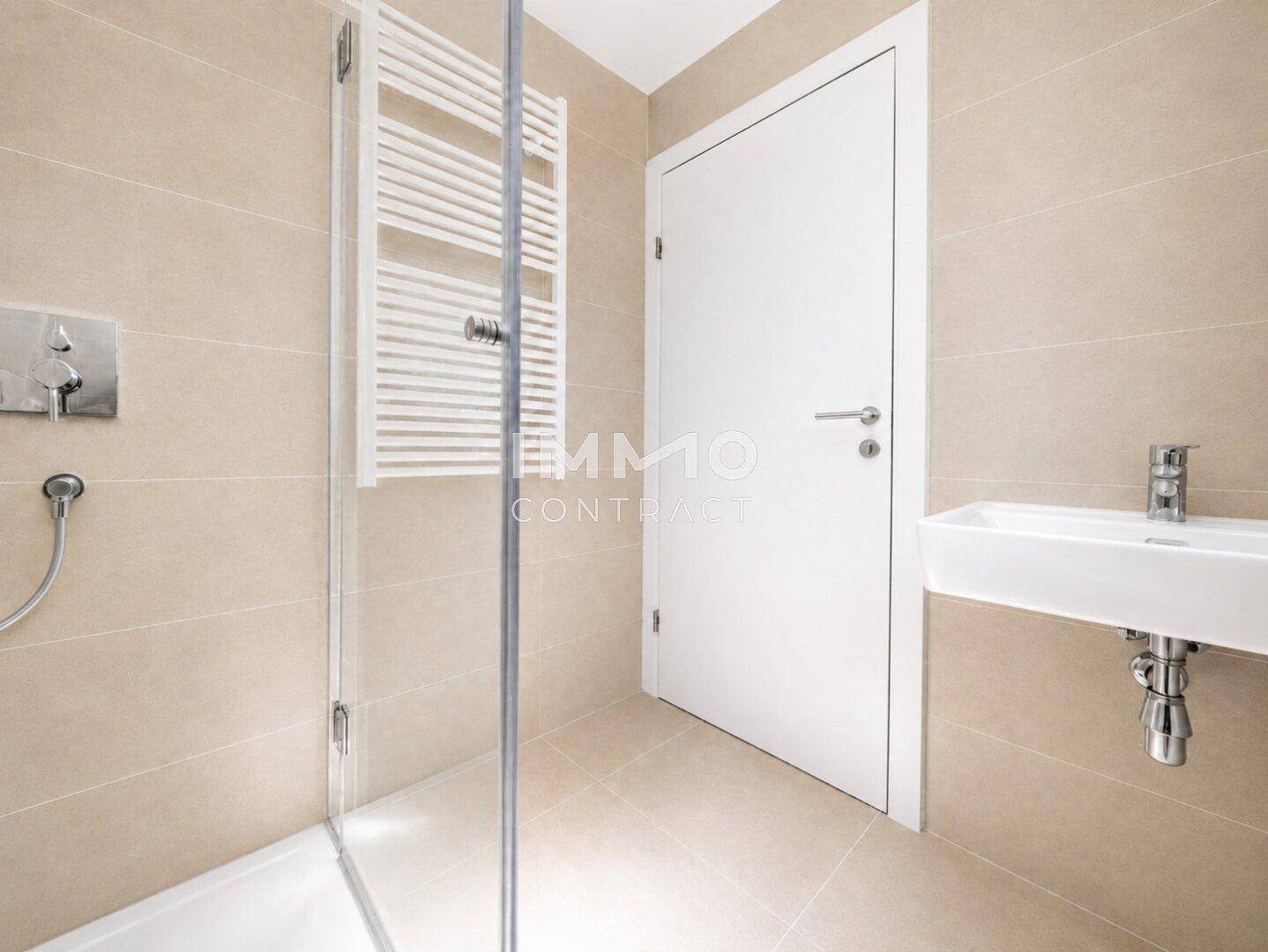 Modernes Badezimmer mit beigefarbenen Fliesen, Dusche und beheiztem Handtuchhalter.