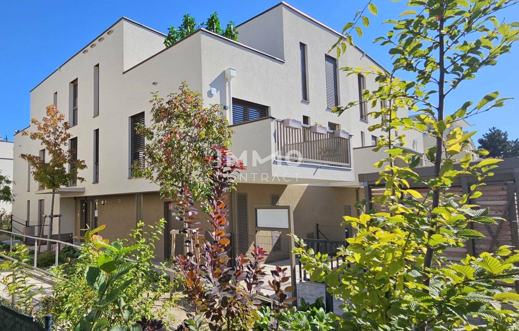 Moderne Wohnanlage mit heller Fassade und gepflegter Bepflanzung im Außenbereich.