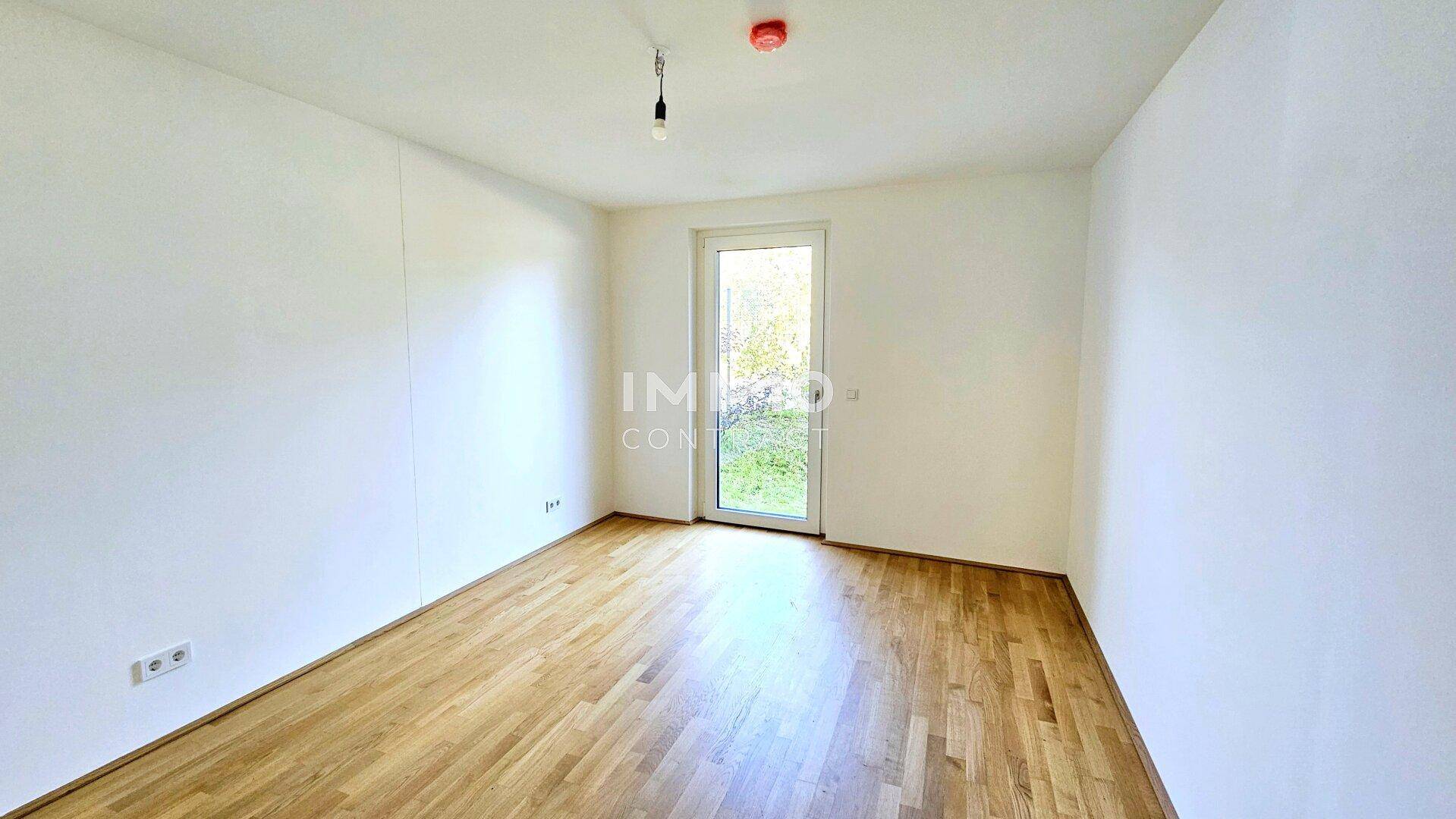 Helles Schlafzimmer mit Holzboden und Zugang zu einem kleinen Außenbereich, ideal für Ruhe.