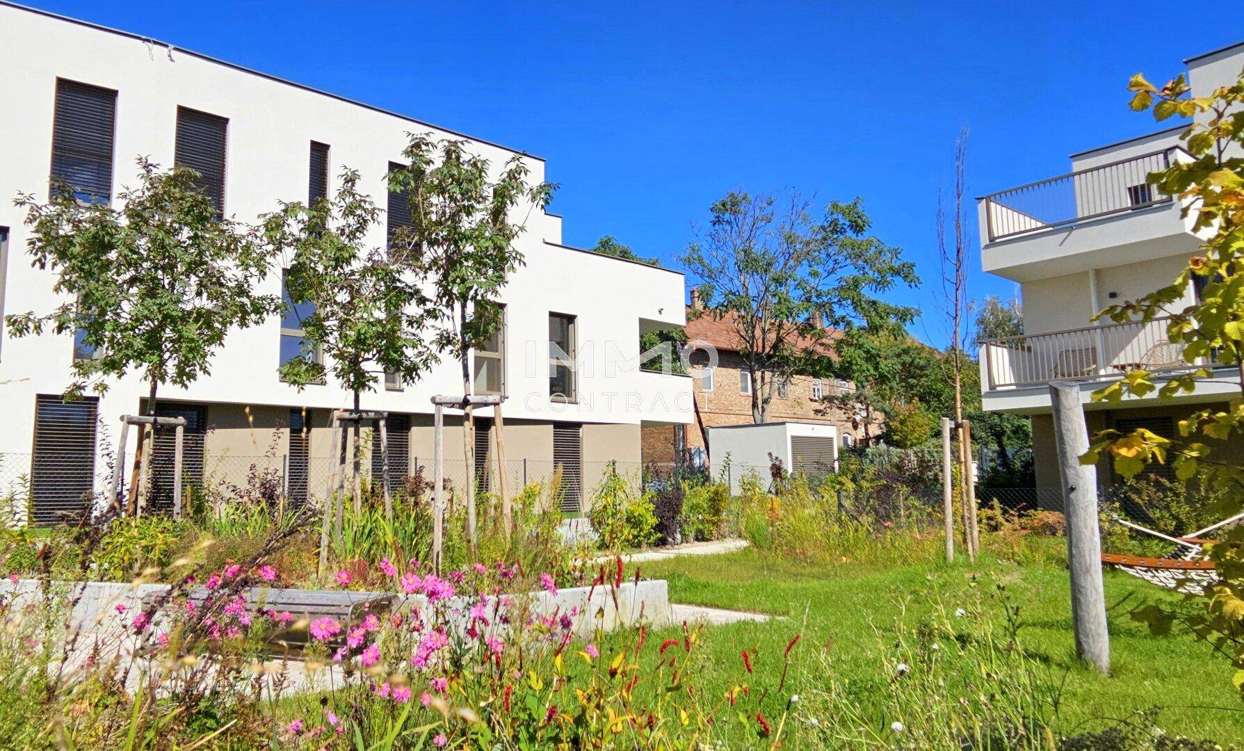 Moderne Wohnanlage mit ansprechender Architektur, eingebettet in eine grüne Gartenlandschaft.