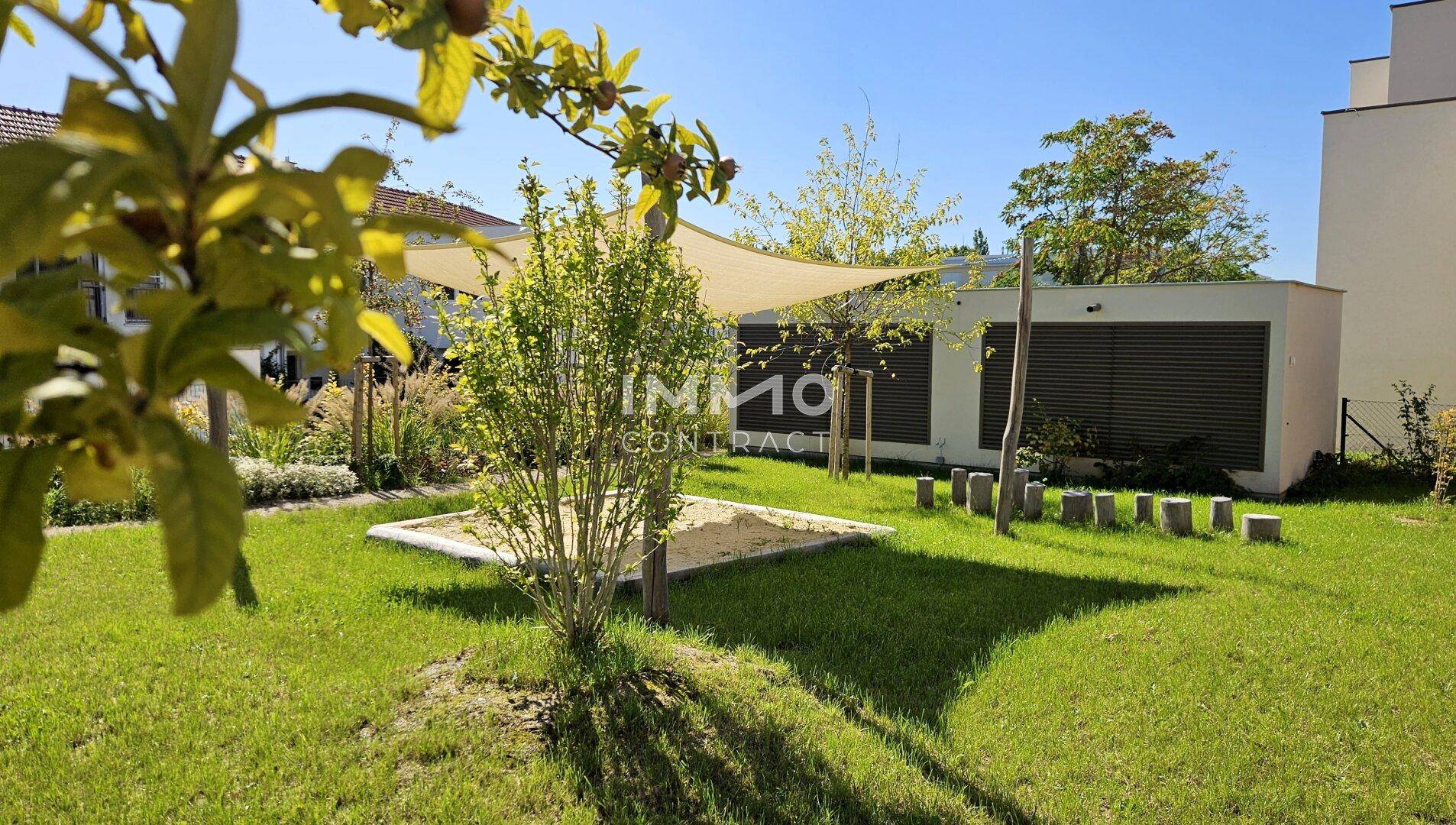 Kinderspielbereich im Garten mit Sandkasten und Sonnensegel, ideal für Familien mit Kindern.