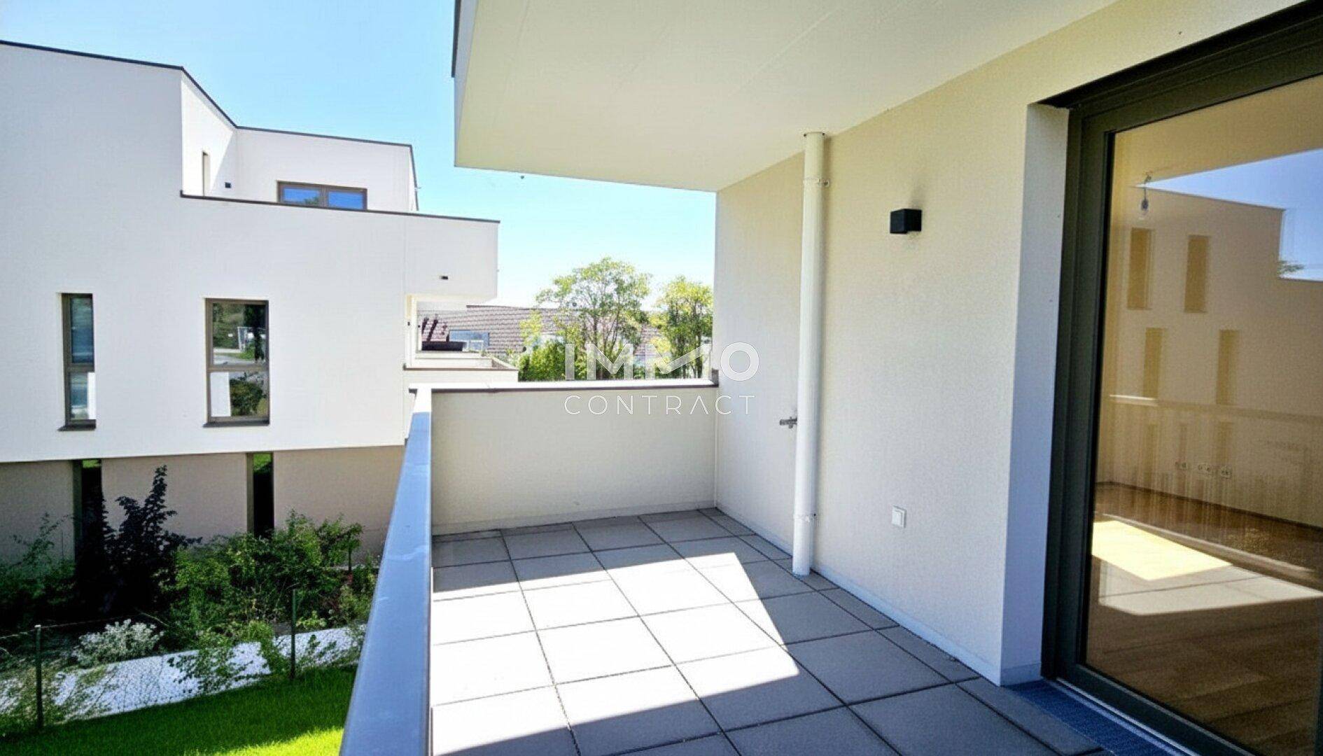 Sonniger Balkon mit Fliesenboden und Blick auf die moderne Architektur des Gebäudekomplexes.