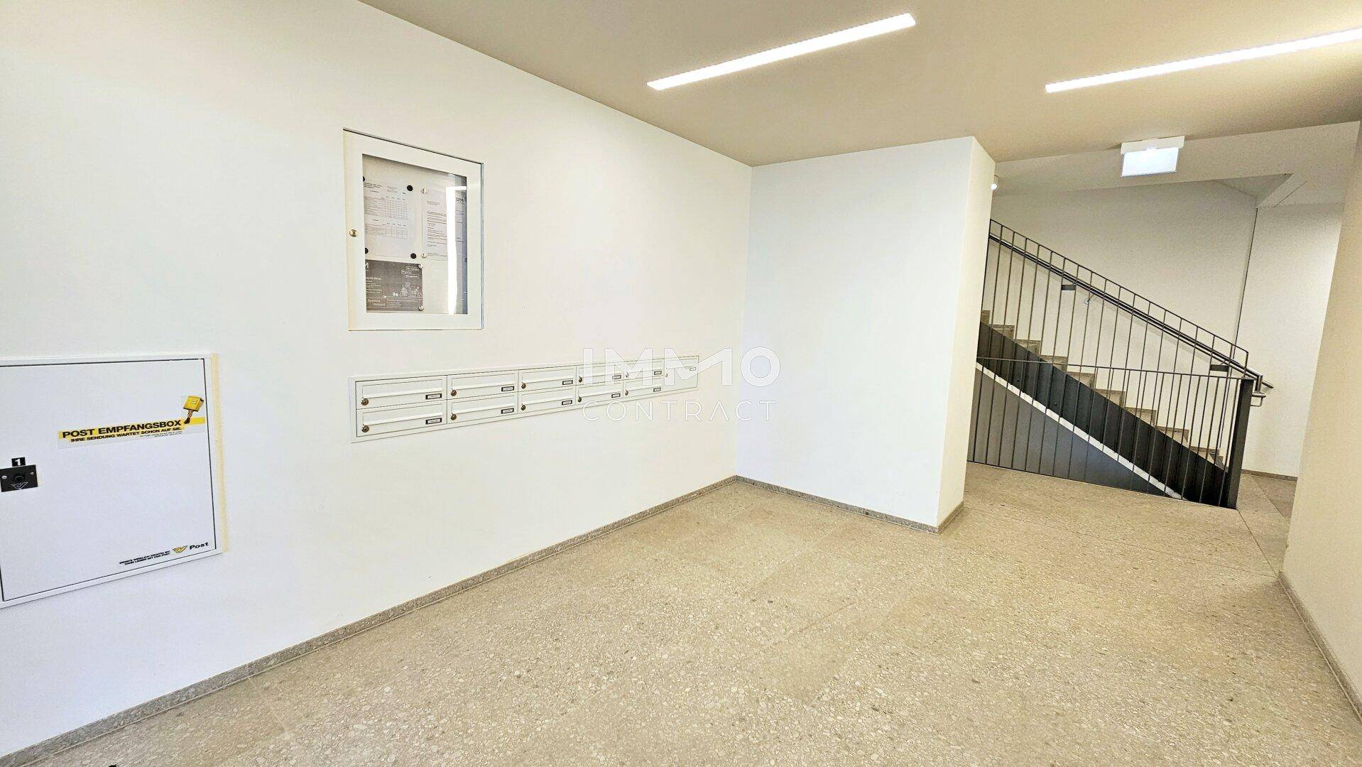 Heller Eingangsbereich mit Briefkästen und Treppenhauszugang in einem modernen Gebäude.