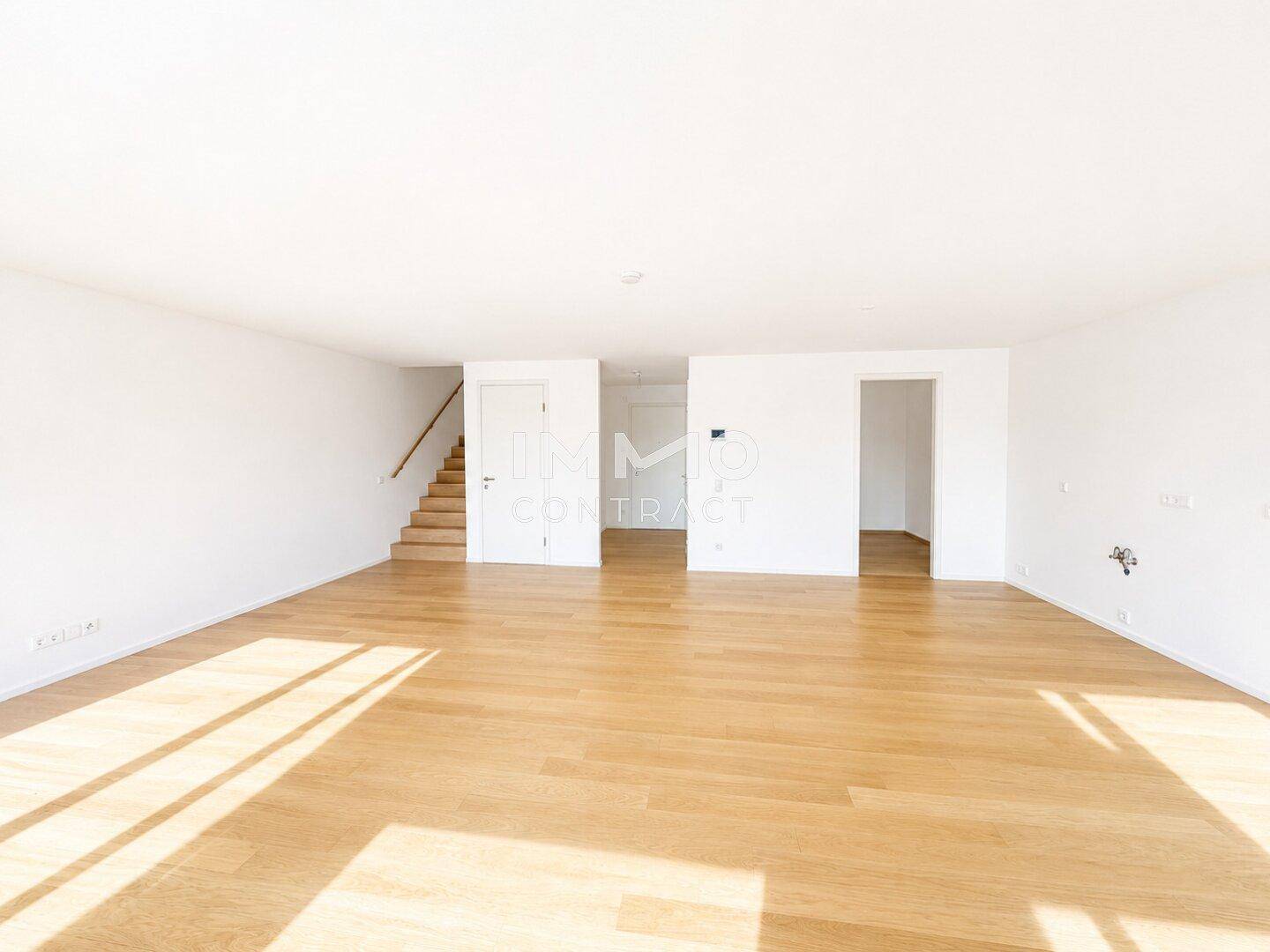 Geräumiger, heller Wohnbereich mit Holzboden und Treppenzugang zu weiteren Etagen.