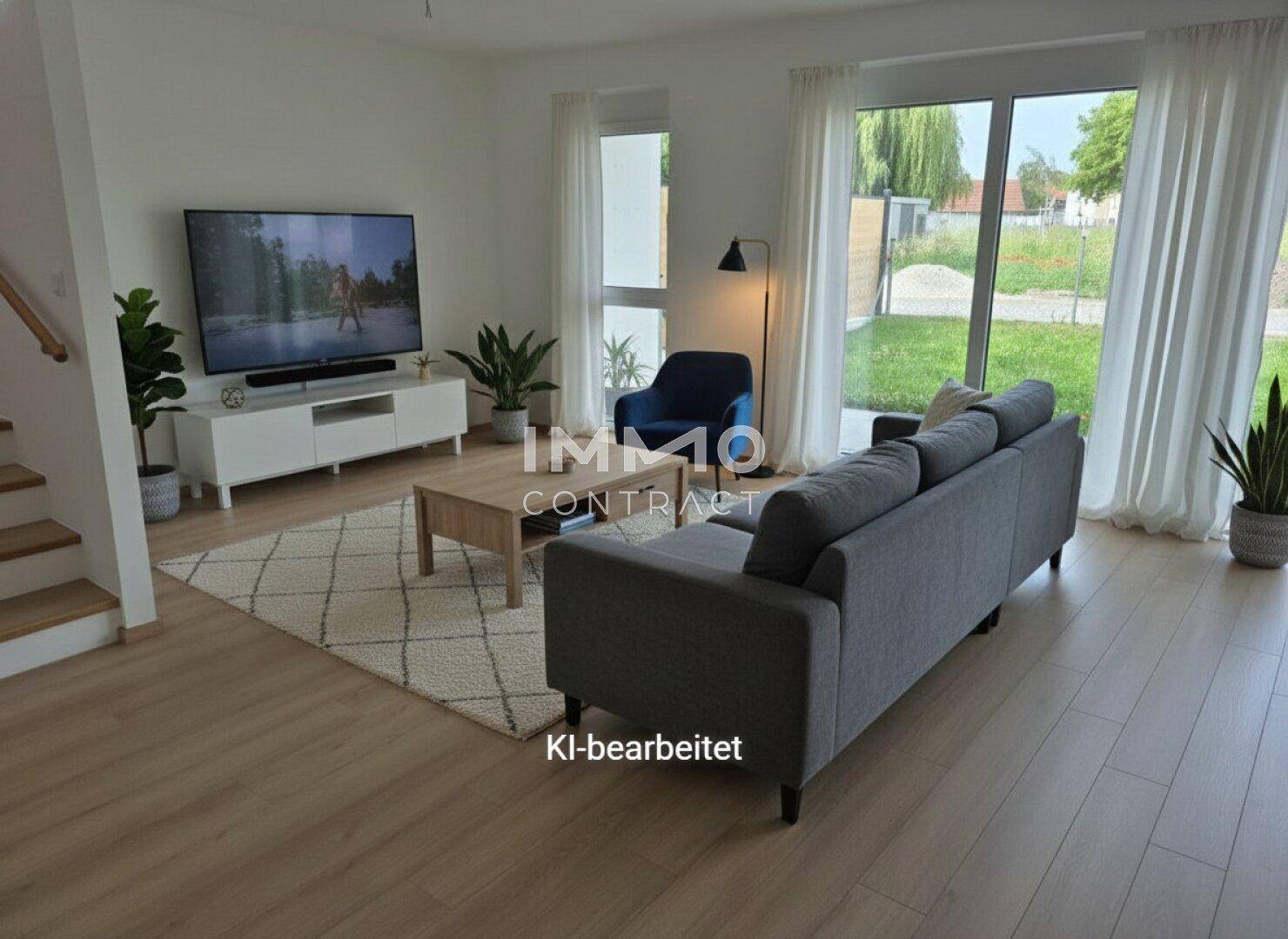 Gemütlich eingerichtetes Wohnzimmer mit Blick ins Grüne, modernem Sofa und großem Fernseher.