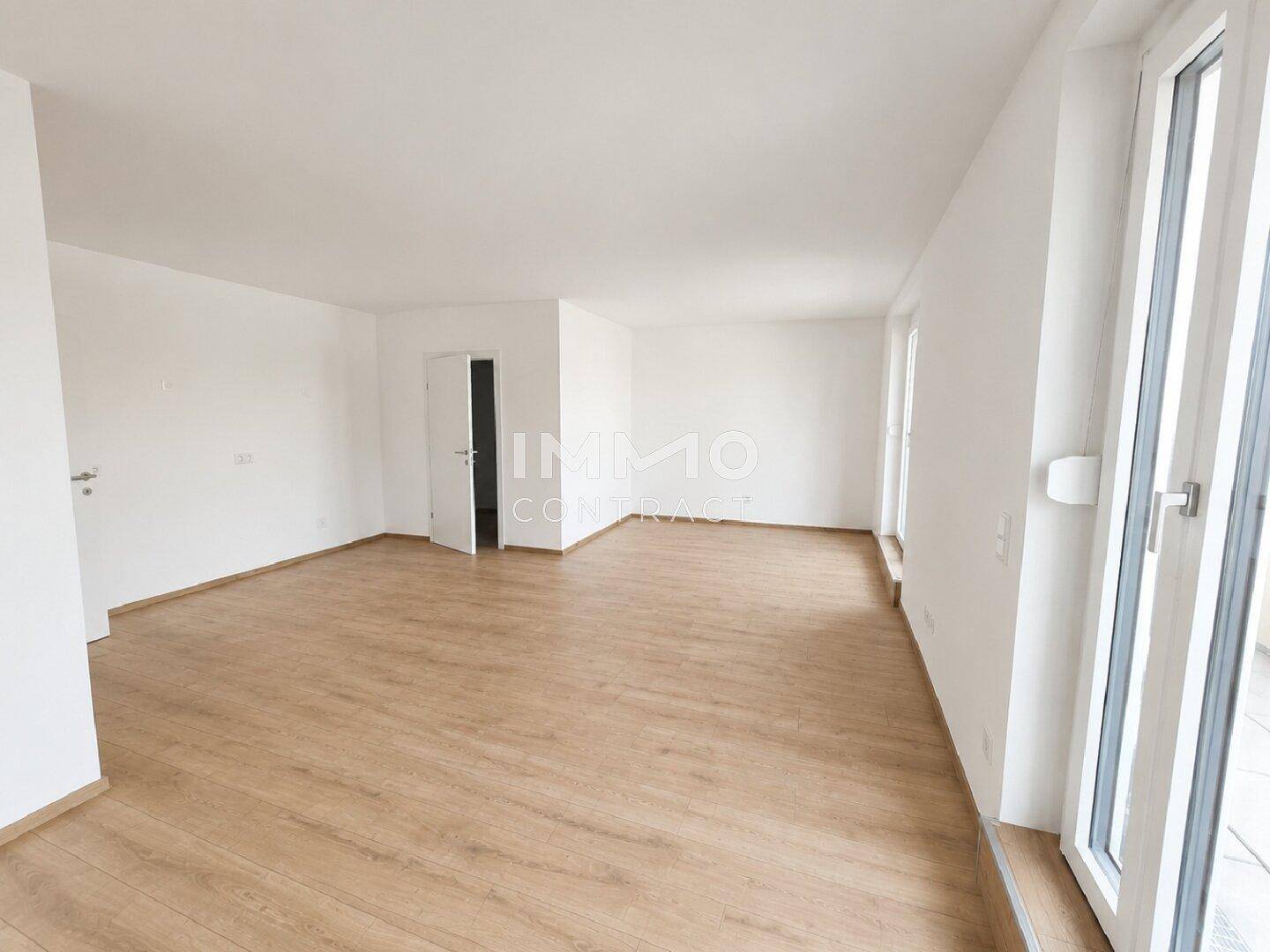 Geräumiger, heller Innenraum mit Holzboden und Zugang zu weiteren Zimmern.