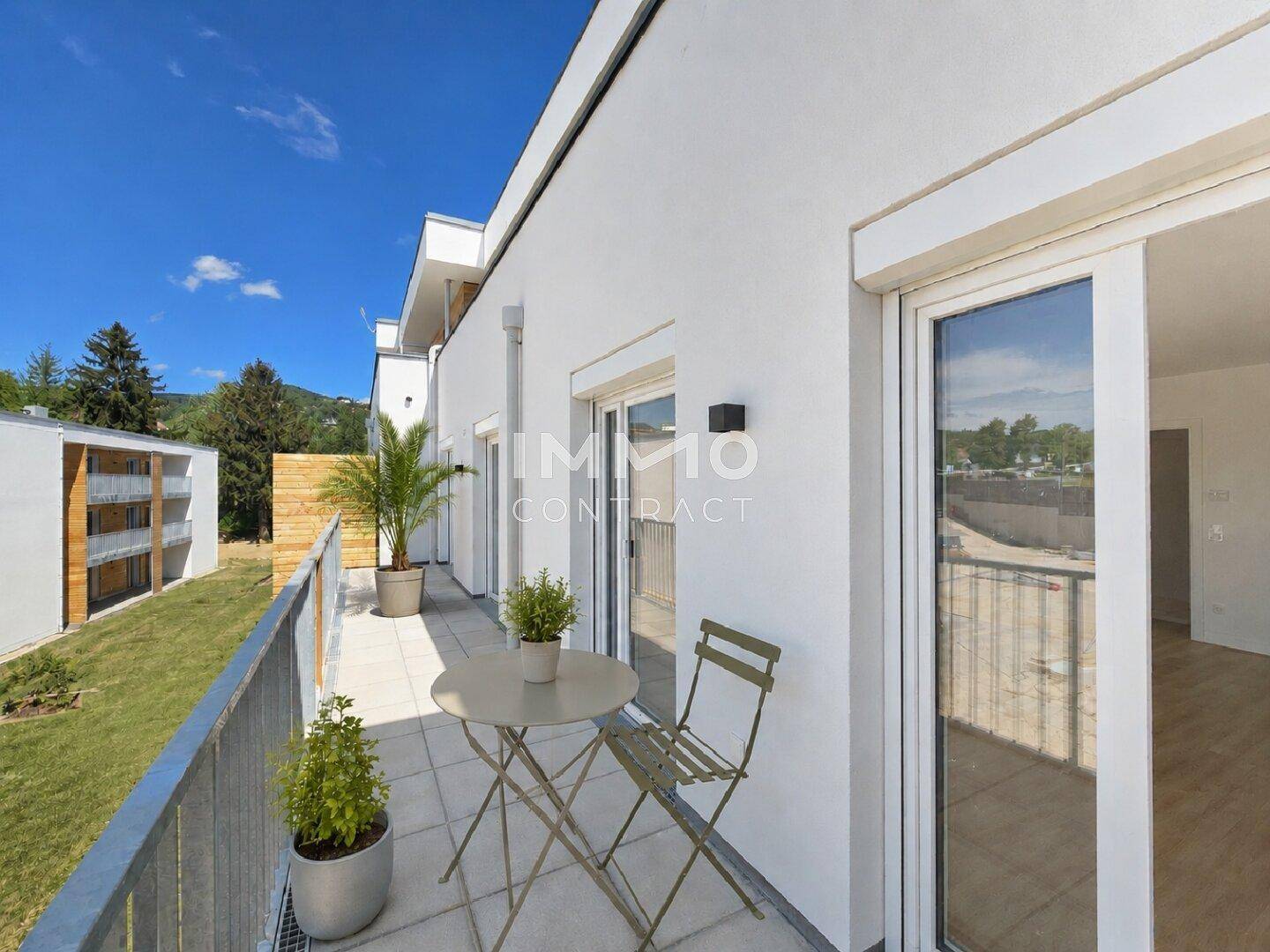 Sonniger Balkon mit Fliesenboden, Sitzgelegenheiten und Blick ins Grüne.