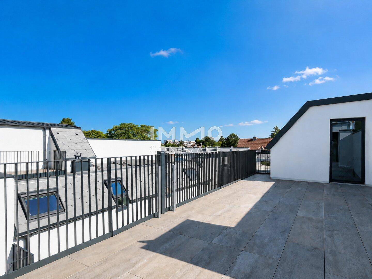 Weitläufige Dachterrasse mit modernen Fliesen und schwarzem Geländer, bietet einen Blick über die Umgebung.