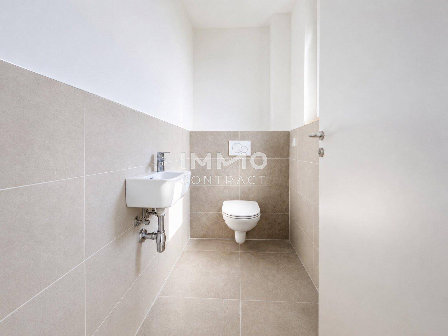 Funktionale Gästetoilette mit modernen Fliesen, wandhängendem WC und einem kleinen Waschbecken.