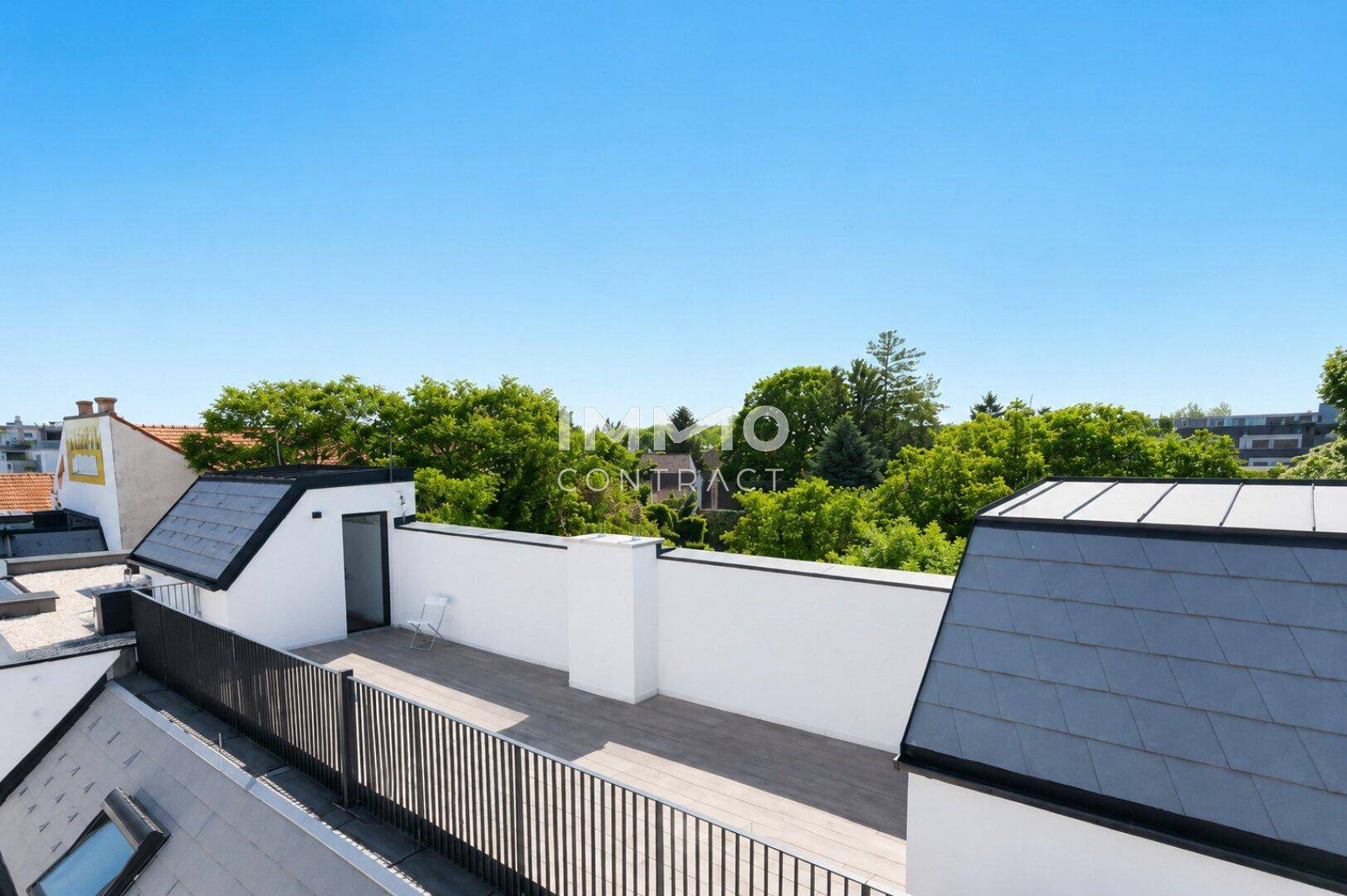 Erhöhter Blick auf eine Dachterrasse mit Holzboden und die grüne Umgebung, ideal für Entspannung.