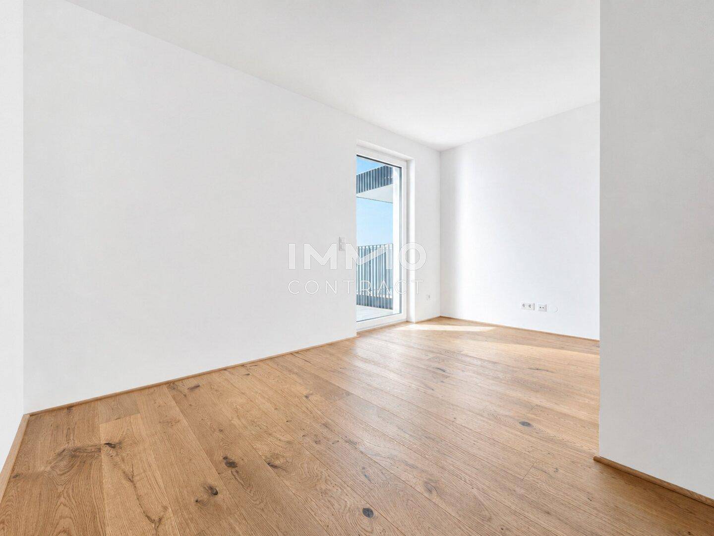 Unmöbliertes Zimmer mit Holzboden und Zugang zu einem französischen Balkon oder einer kleinen Terrasse.