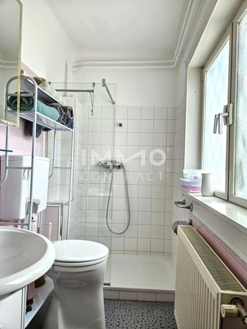 Funktionales Badezimmer mit Dusche, WC, Waschbecken und einem Fenster für Tageslicht.