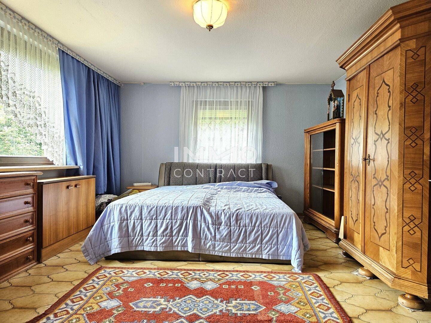 Gemütliches Schlafzimmer mit Doppelbett, traditionellen Holzmöbeln und einem farbigen Teppich.