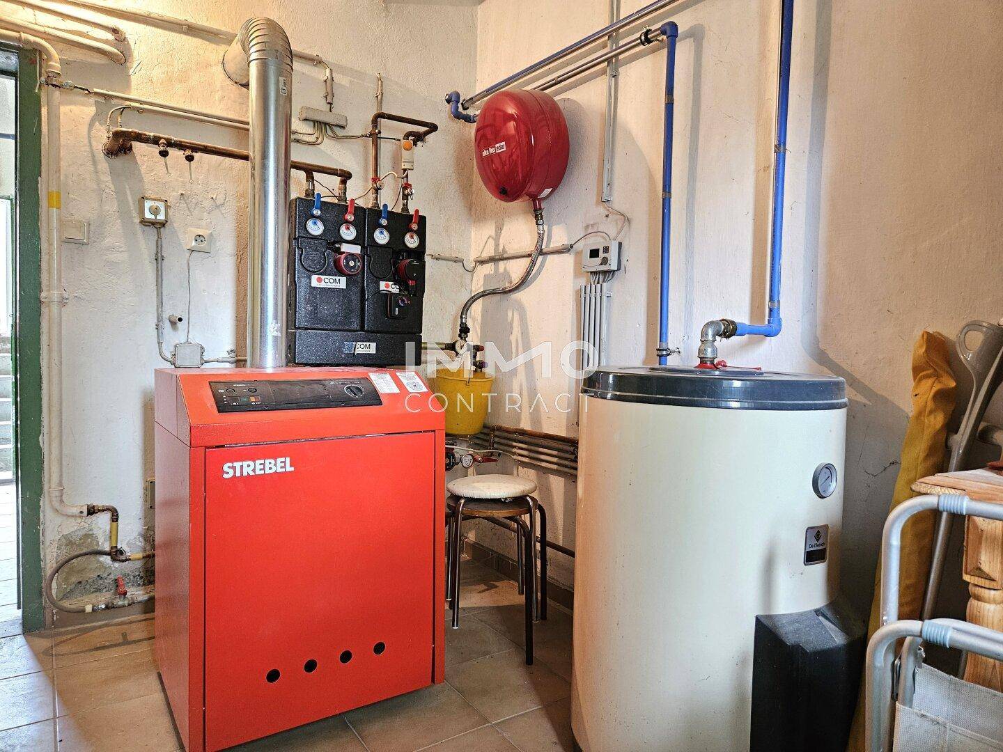 Heizungsraum im Keller mit einem modernen Heizkessel und Warmwasserspeicher.