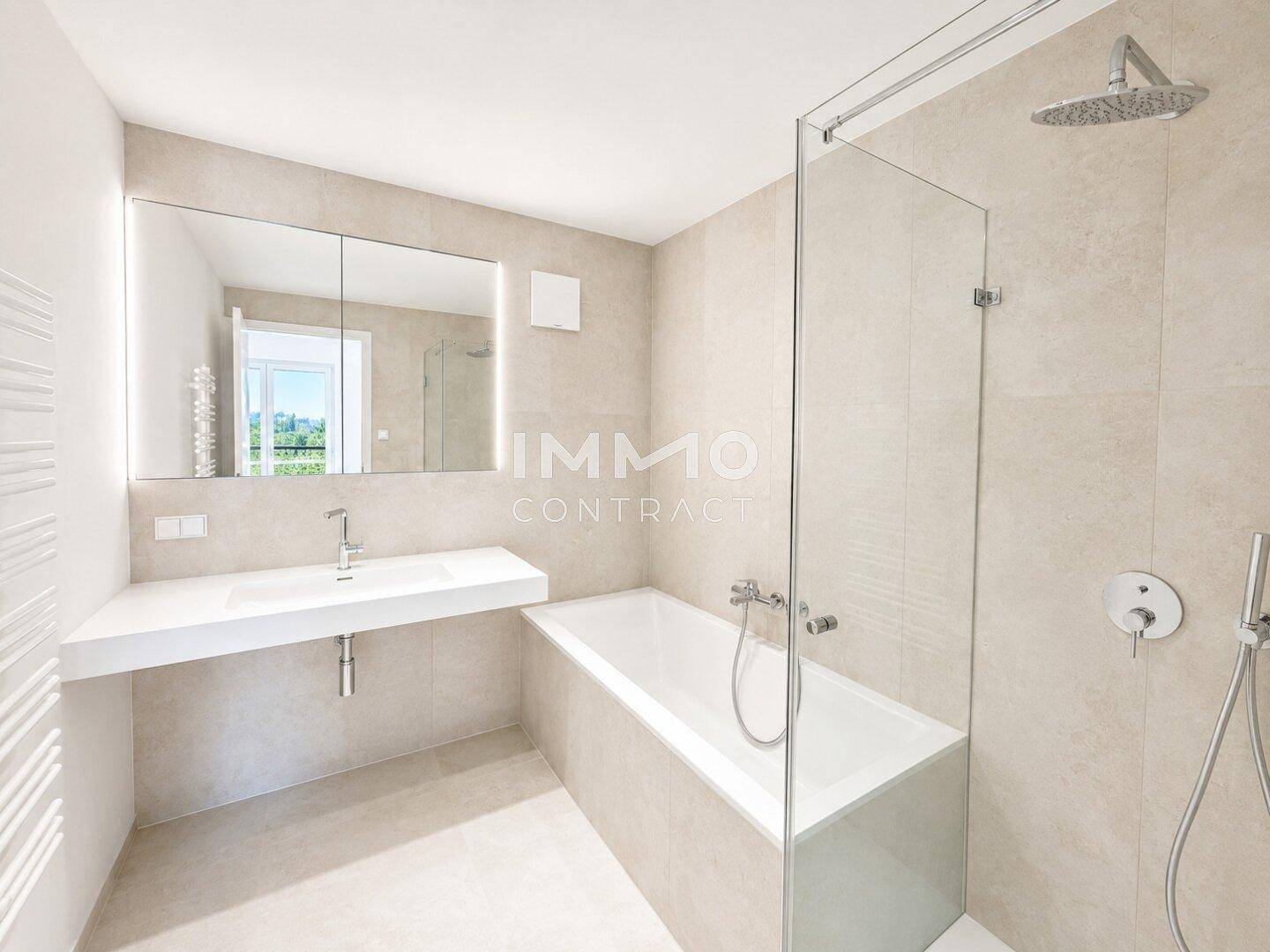 Modernes Badezimmer mit Badewanne, Regendusche und großem Spiegelschrank.